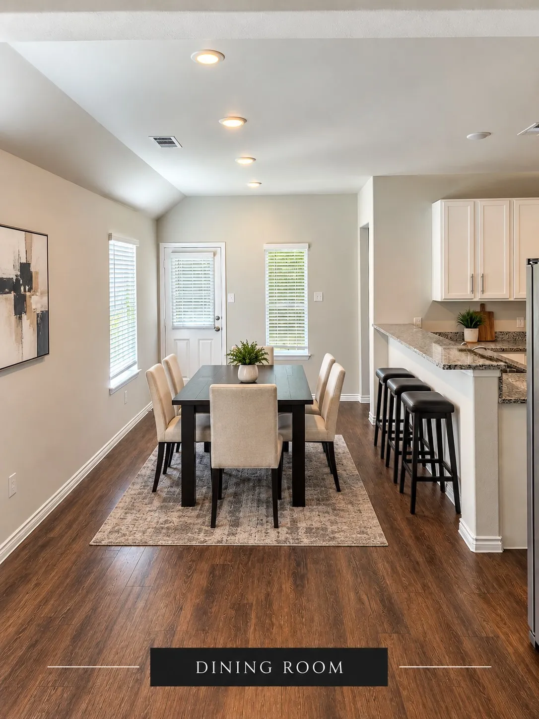 Vaulted ceiling with recessed lighting, wood-finish flooring, white kitchen cabinetry, and a peninsula with countertop seating
