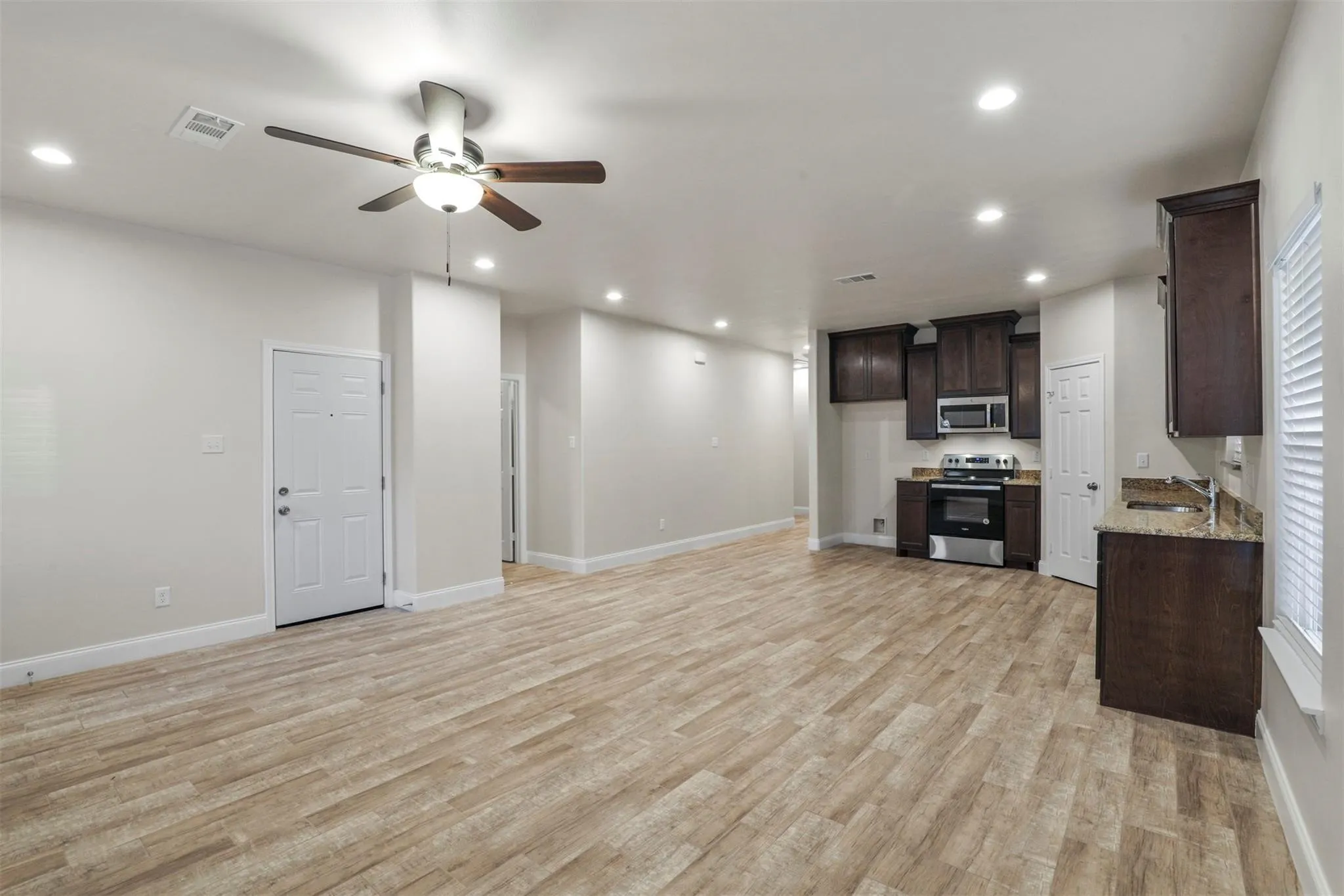 Open concept living area featuring wood-finish flooring, recessed lighting, and a ceiling fan