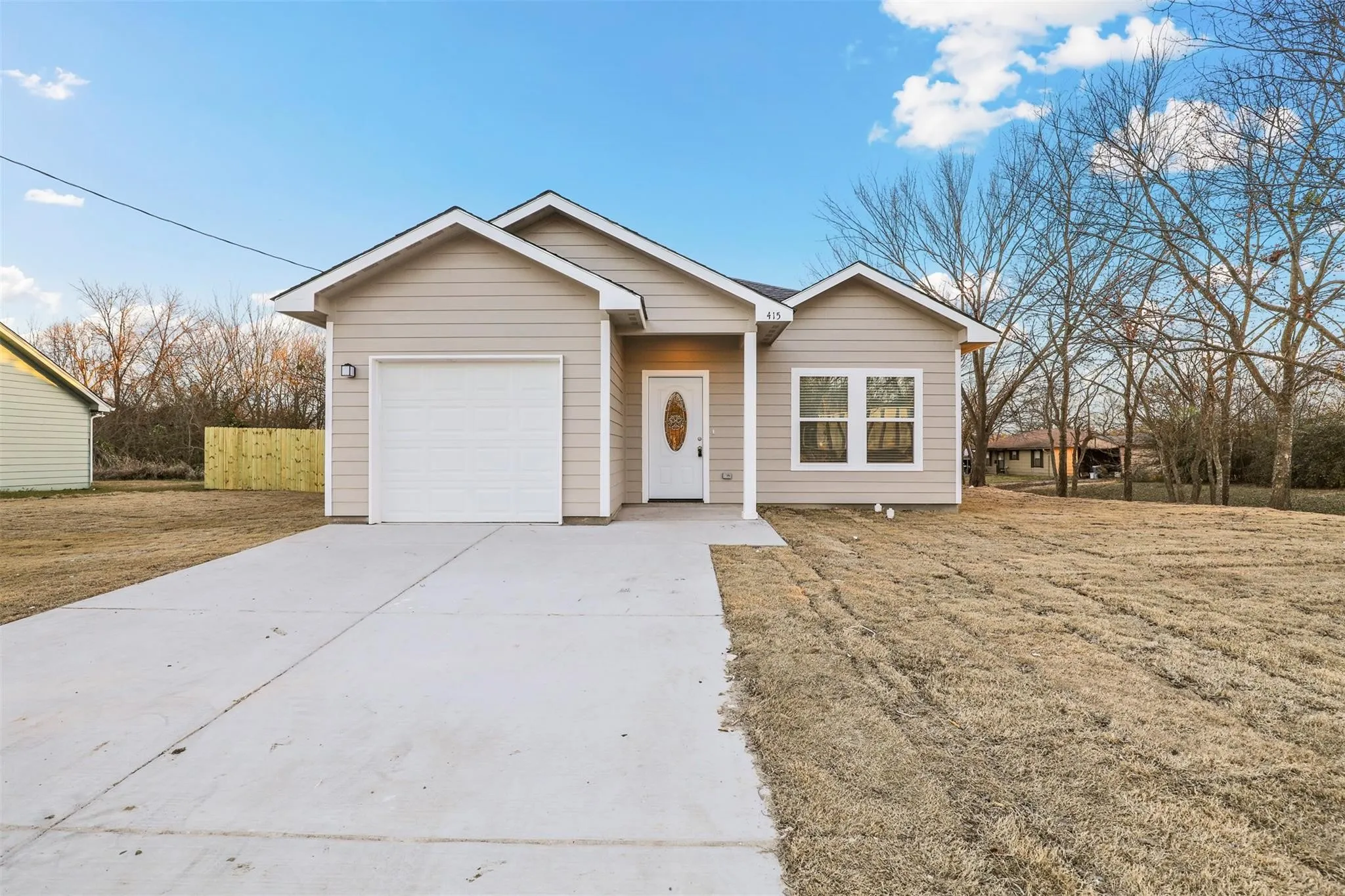 Siding exterior with a single-car garage, concrete driveway, and an oval-paneled front door