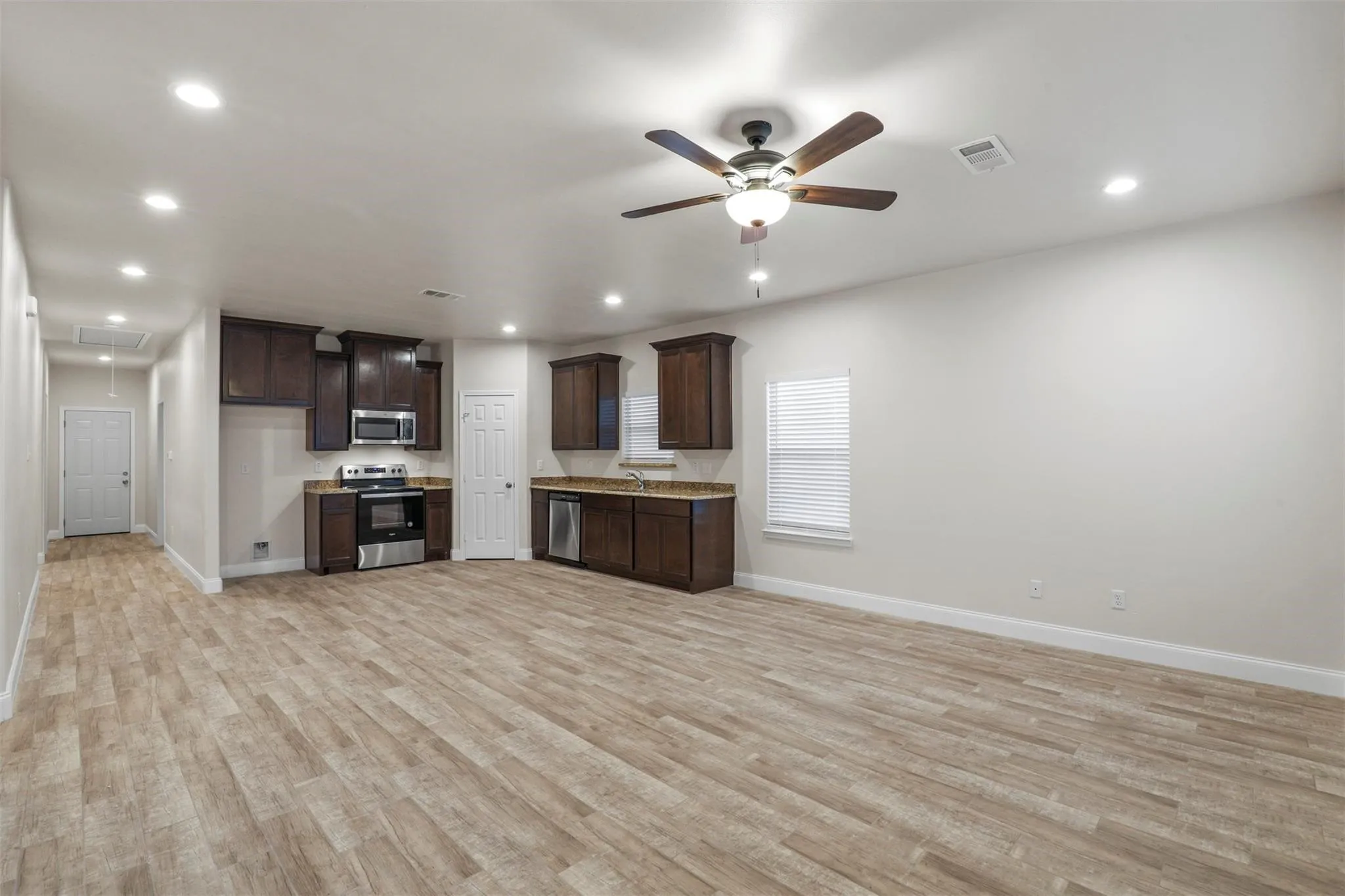 Open-concept living space with wood-finish flooring, recessed lighting, and a ceiling fan