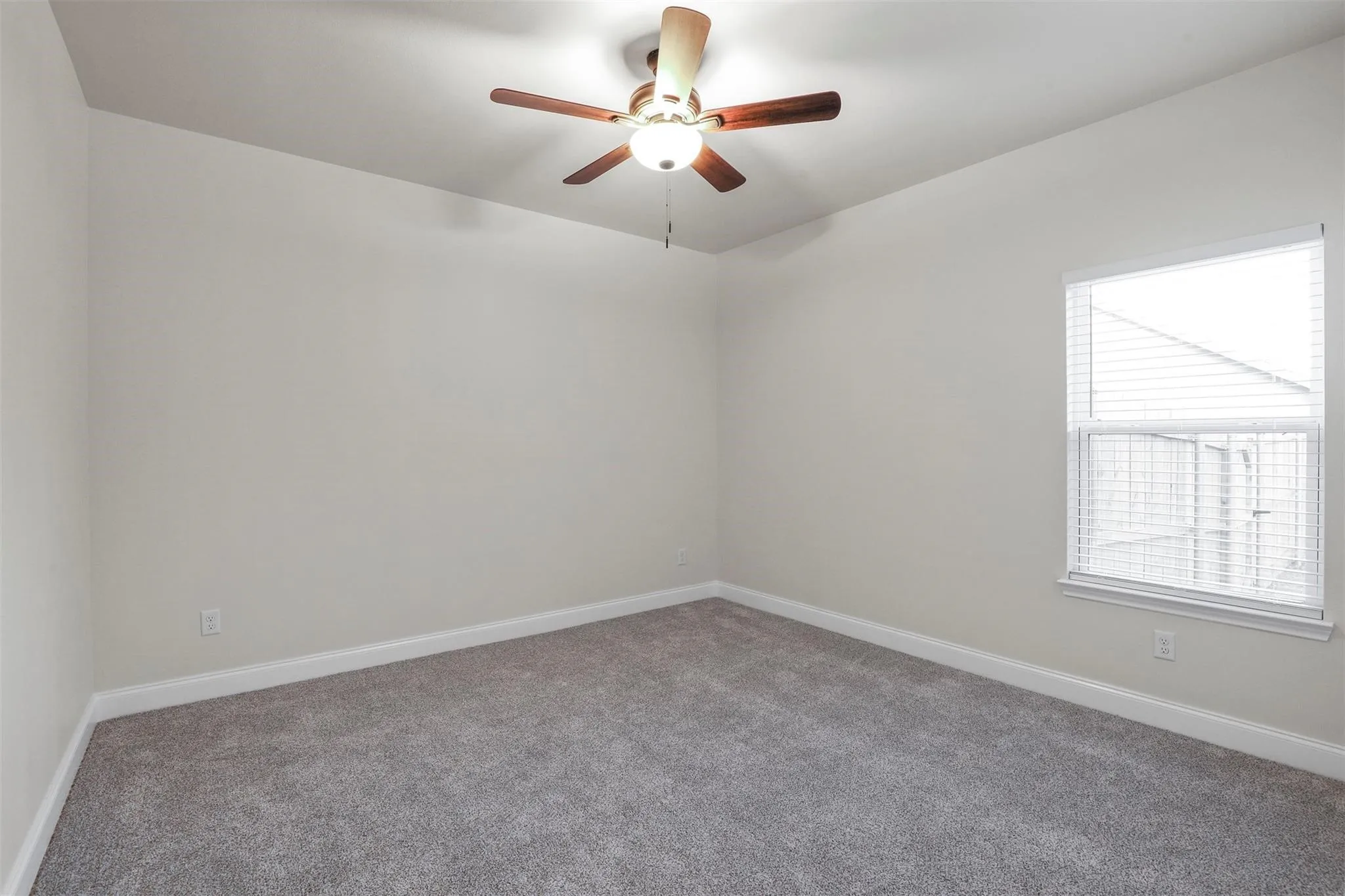Neutral wall paint, gray carpet flooring, ceiling fan with integrated lighting, and window with blinds