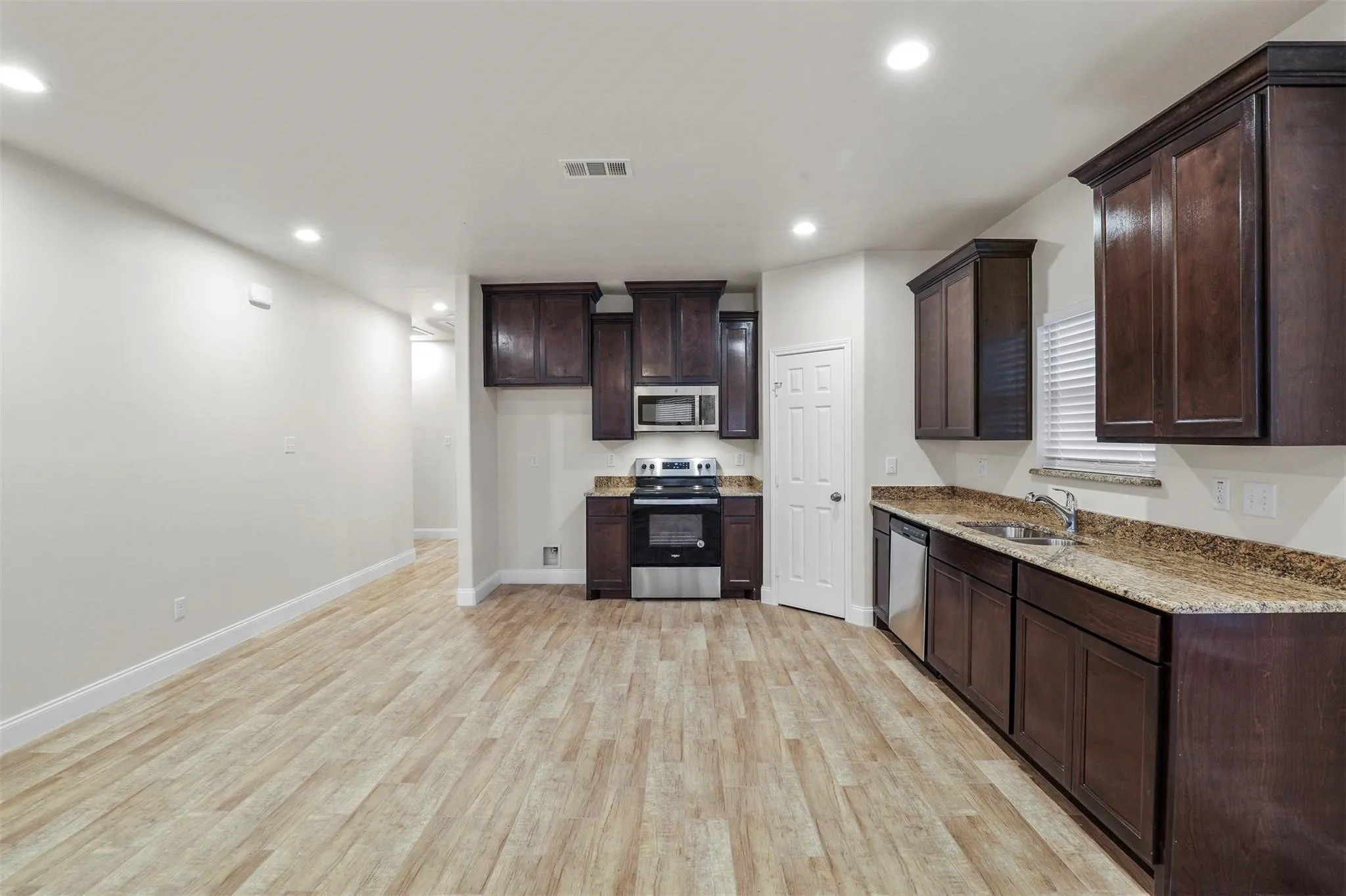 Kitchen with dark wood-finish cabinetry, granite countertops, and stainless steel appliances