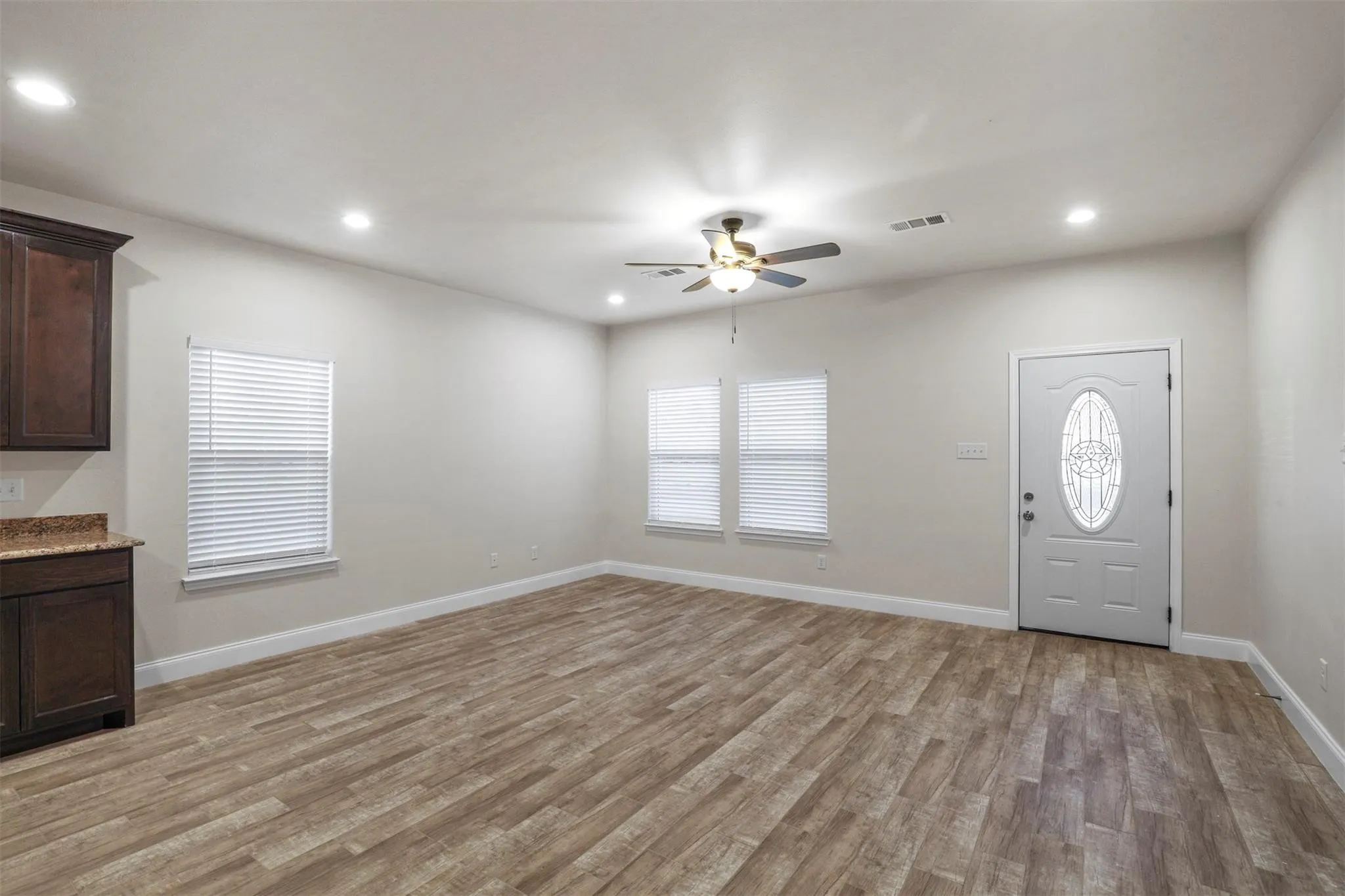 Expansive room featuring wood-finish flooring, recessed lighting, and a ceiling fan