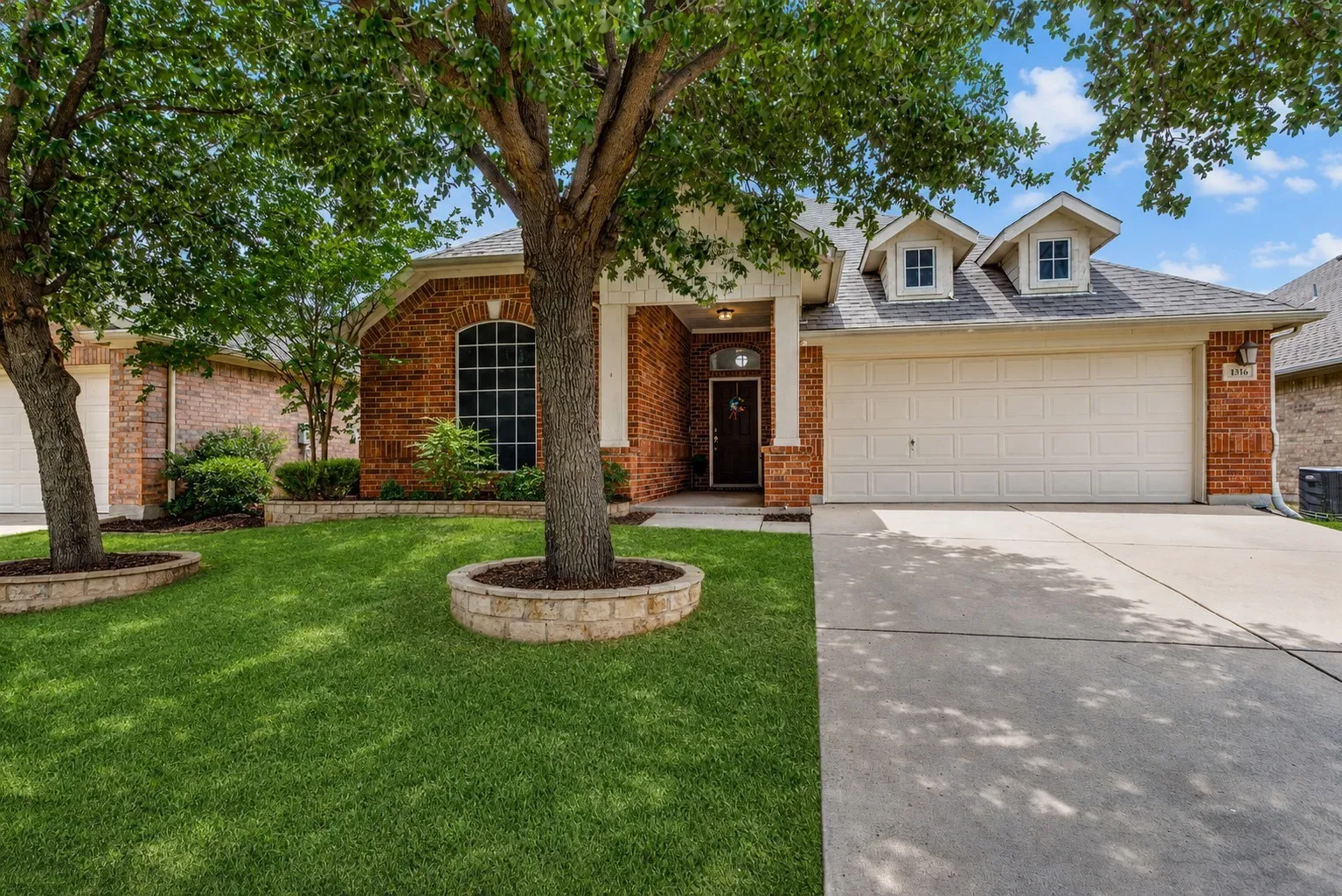 Brick exterior with white trim, a two-car garage, and a concrete driveway
