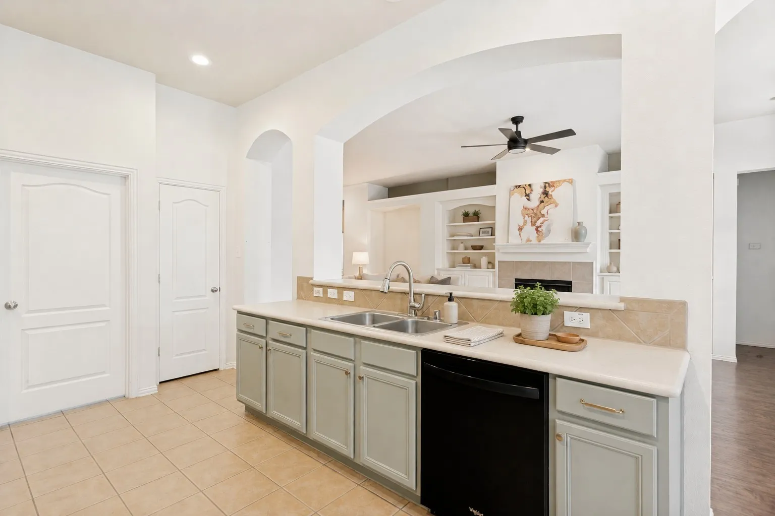 Kitchen with light-colored cabinetry, double basin sink, and black dishwasher