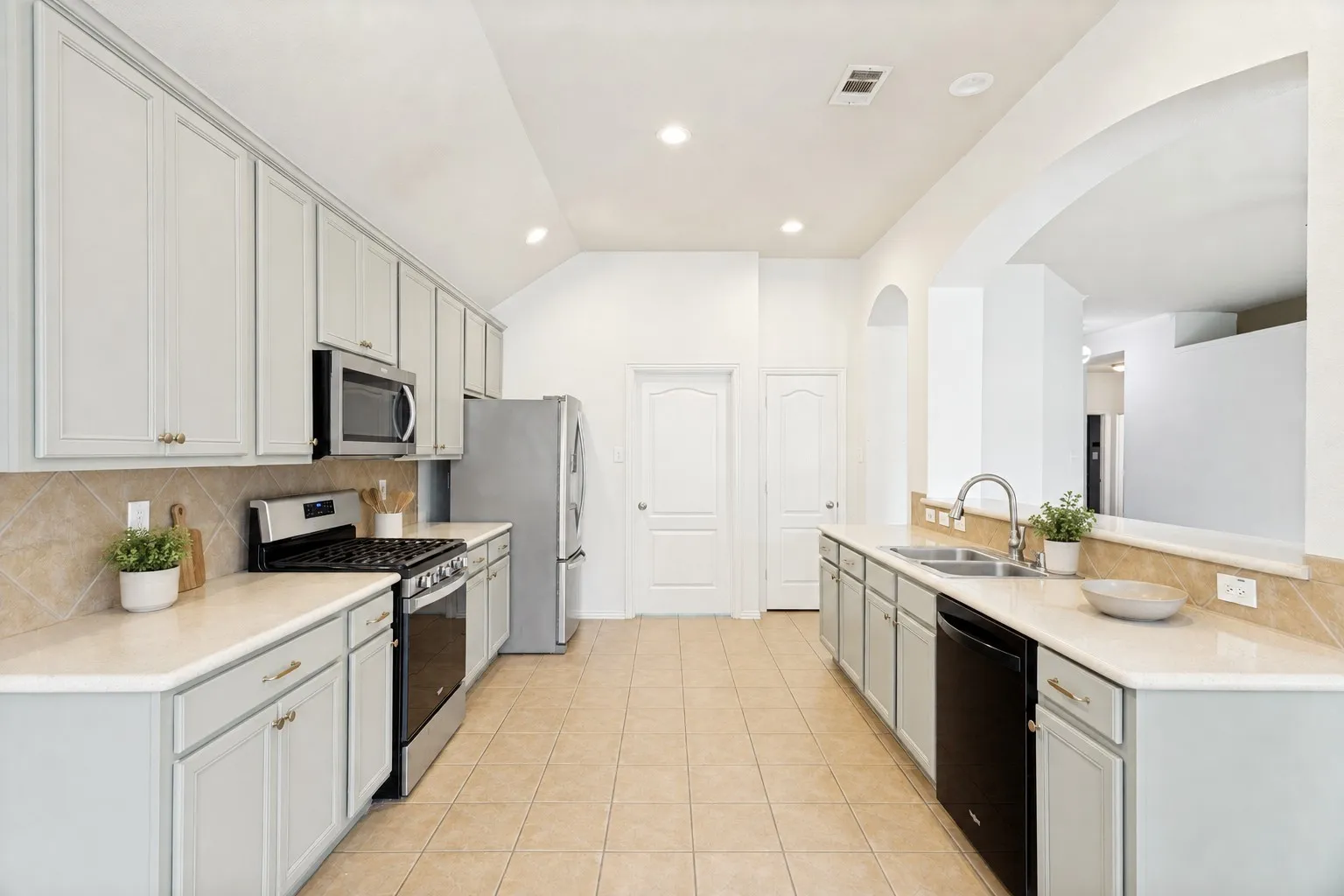 Contemporary kitchen featuring light-toned cabinetry, stainless steel appliances, white countertops, and a tiled backsplash