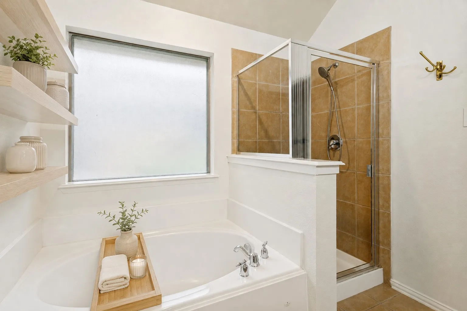 Built-in bathtub with deck-mounted fixtures, separate glass-enclosed shower with tile surround, and floating wood shelves