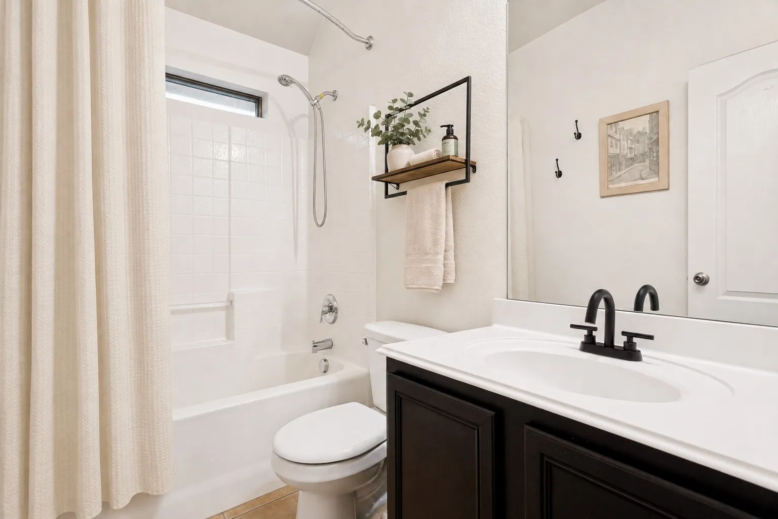 Tub/shower combination with white subway tile surround, dark wood-finish vanity with white countertop, and black fixtures