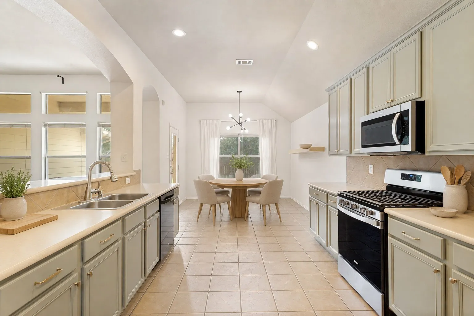 Spacious kitchen featuring light-toned cabinetry, stainless steel appliances, tile flooring, and a tile backsplash