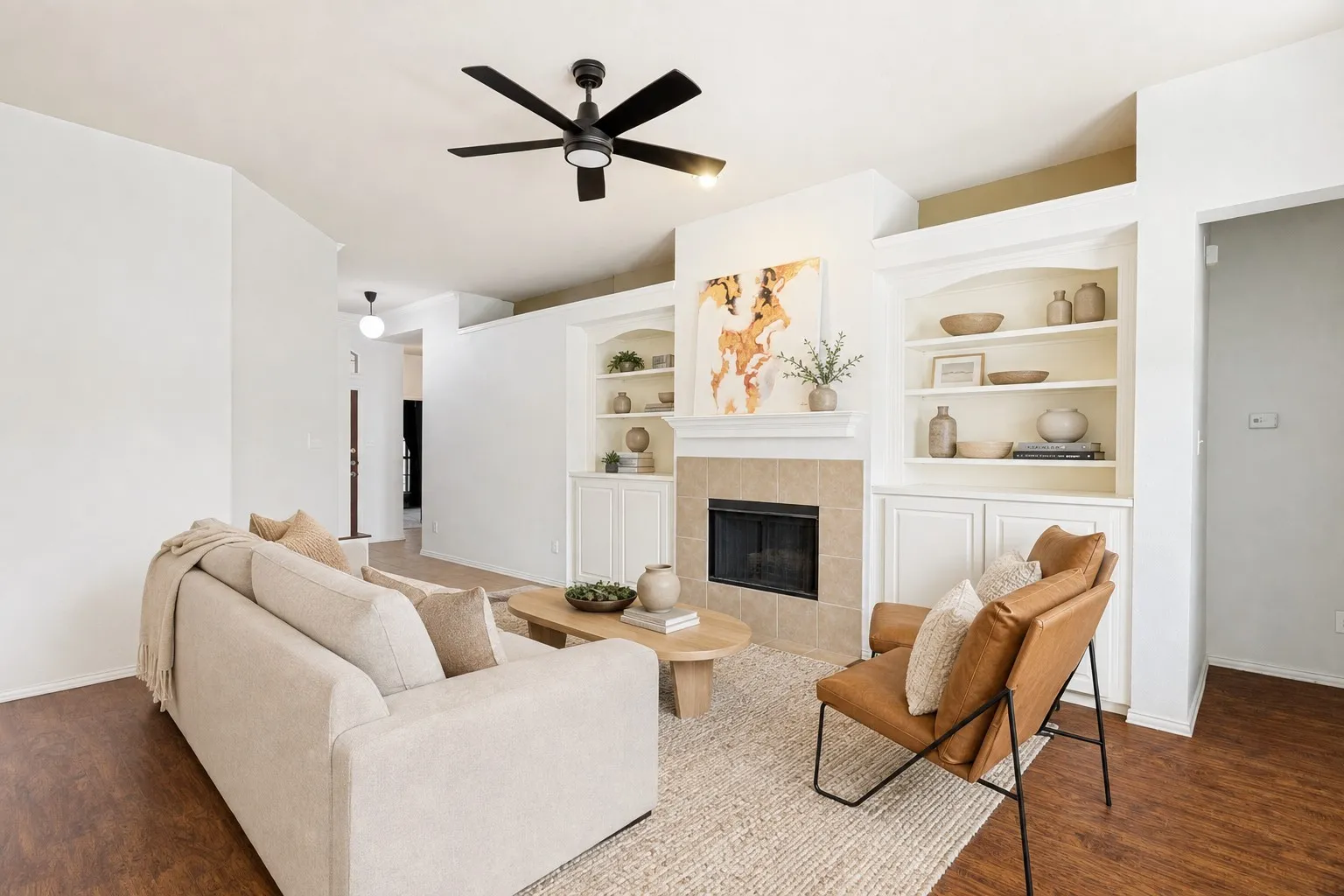 Living space featuring a fireplace with a tile surround, built-in shelving, built-in cabinetry, dark wood-finish flooring, and a ceiling fan