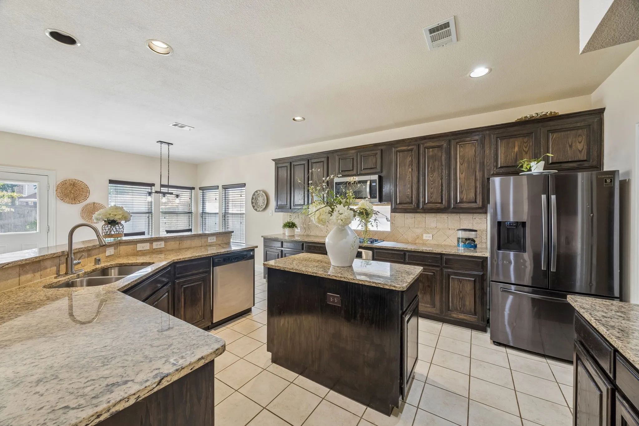 Kitchen featuring dark wood cabinetry, granite countertops, a center island, stainless steel appliances, and tile flooring