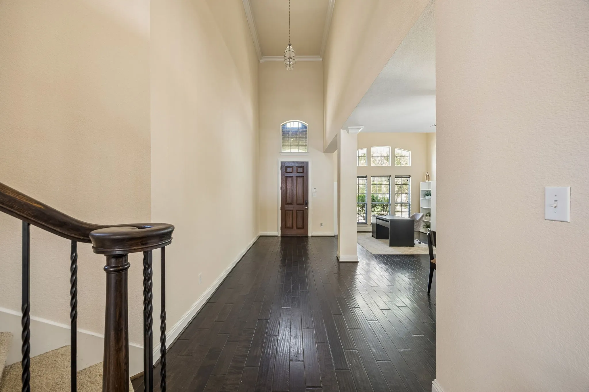 Two-story foyer featuring dark wood-finish flooring, a grand arched entryway, and a decorative light fixture