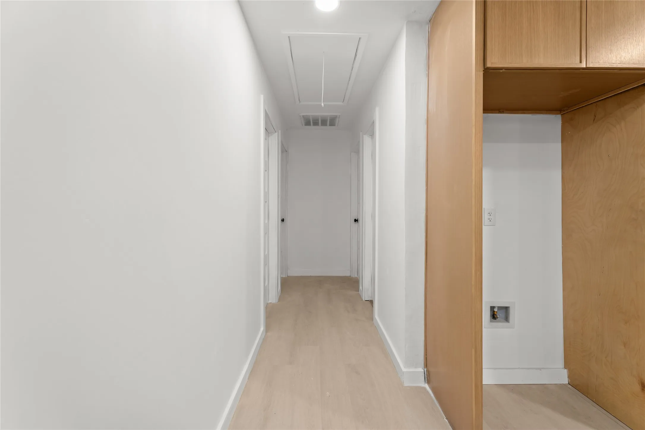 Light wood-finish flooring, recessed lighting, white walls, and built-in wood cabinetry