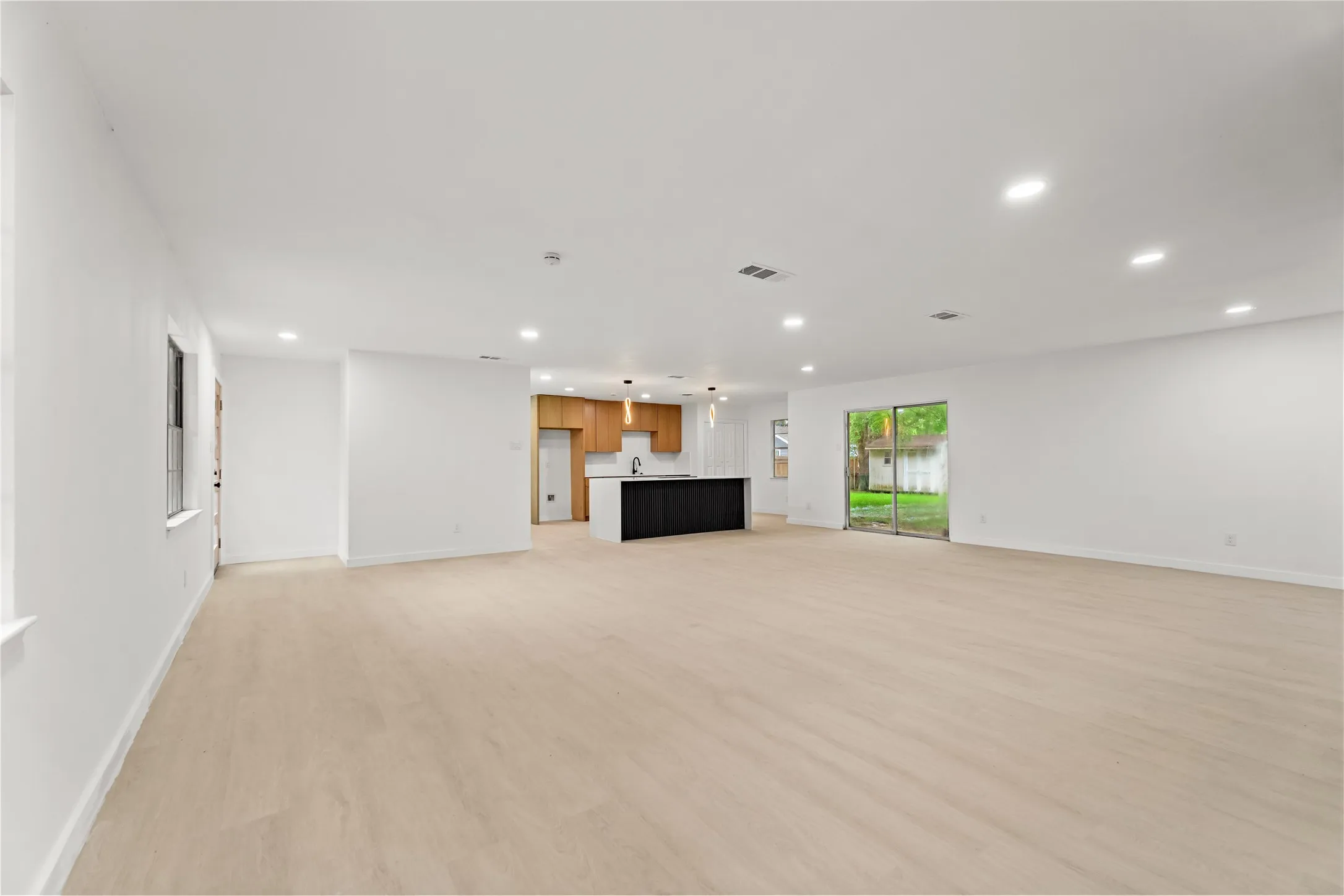 Open-concept living space featuring light wood-finish flooring, recessed ceiling lighting, and white walls