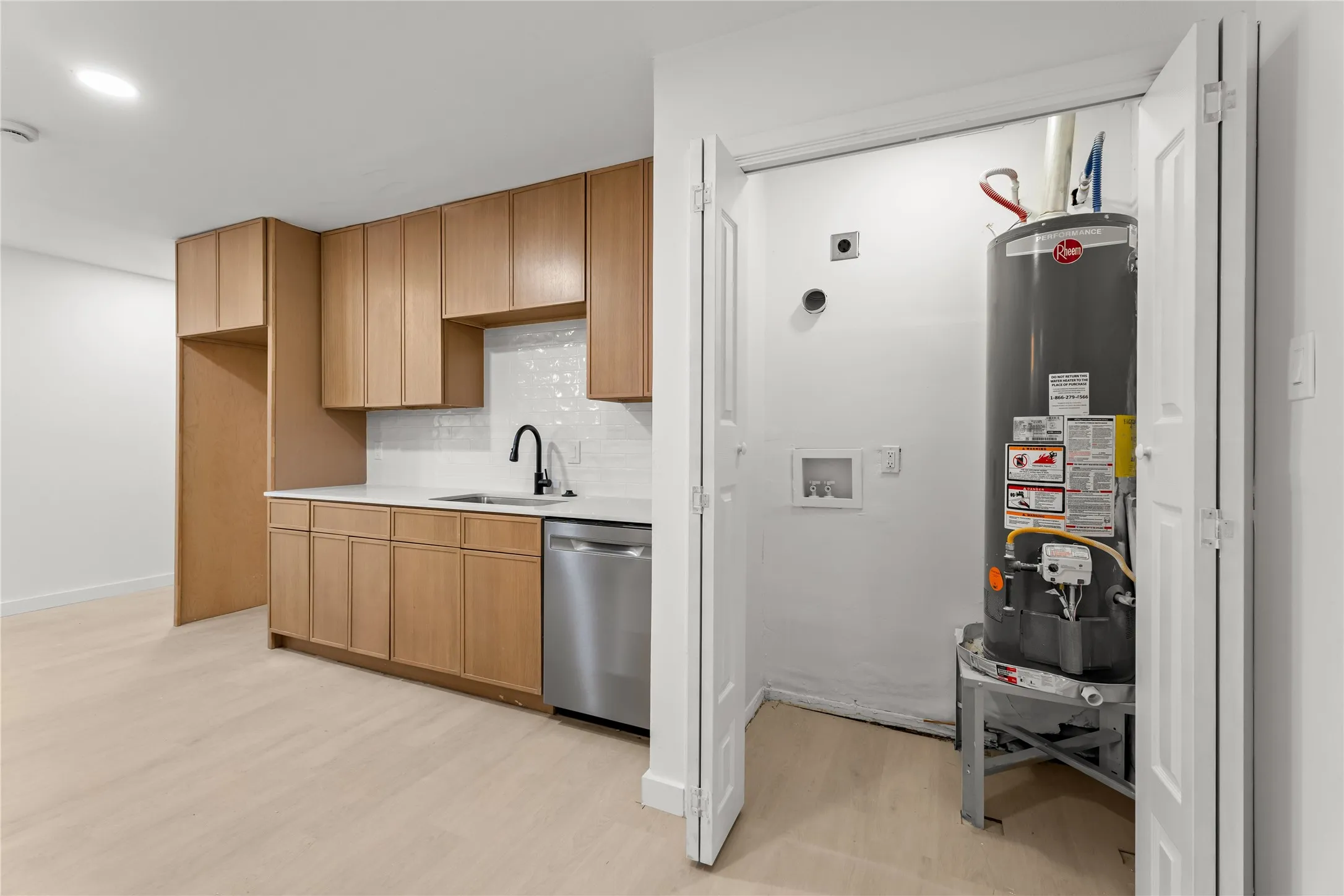 Kitchenette featuring light wood cabinetry, white countertops, and a subway tile backsplash