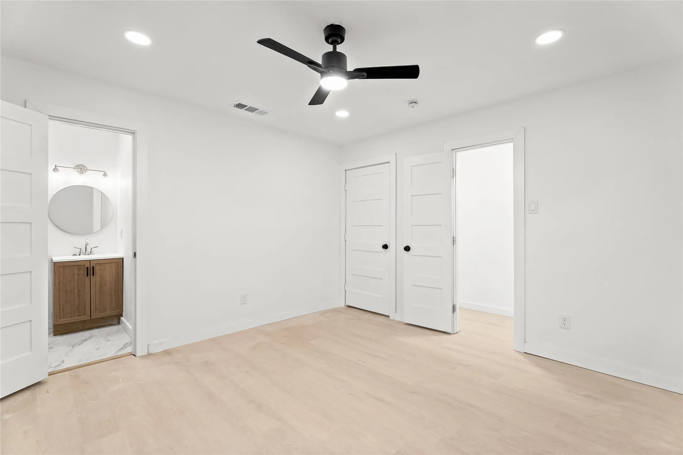 Recessed lighting, light wood-finish flooring, and a ceiling fan with matte black finish