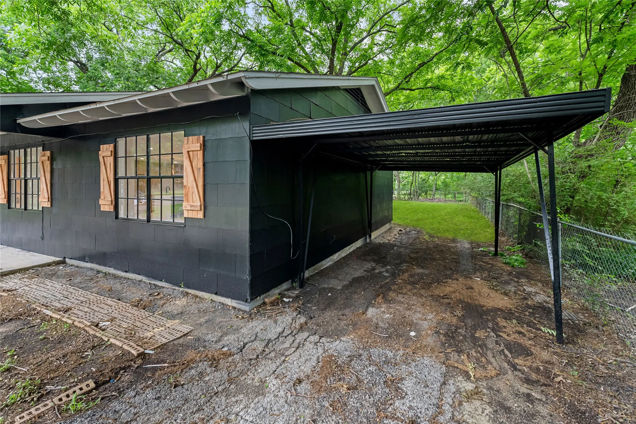 Dark exterior siding with multiple windows featuring wood shutters