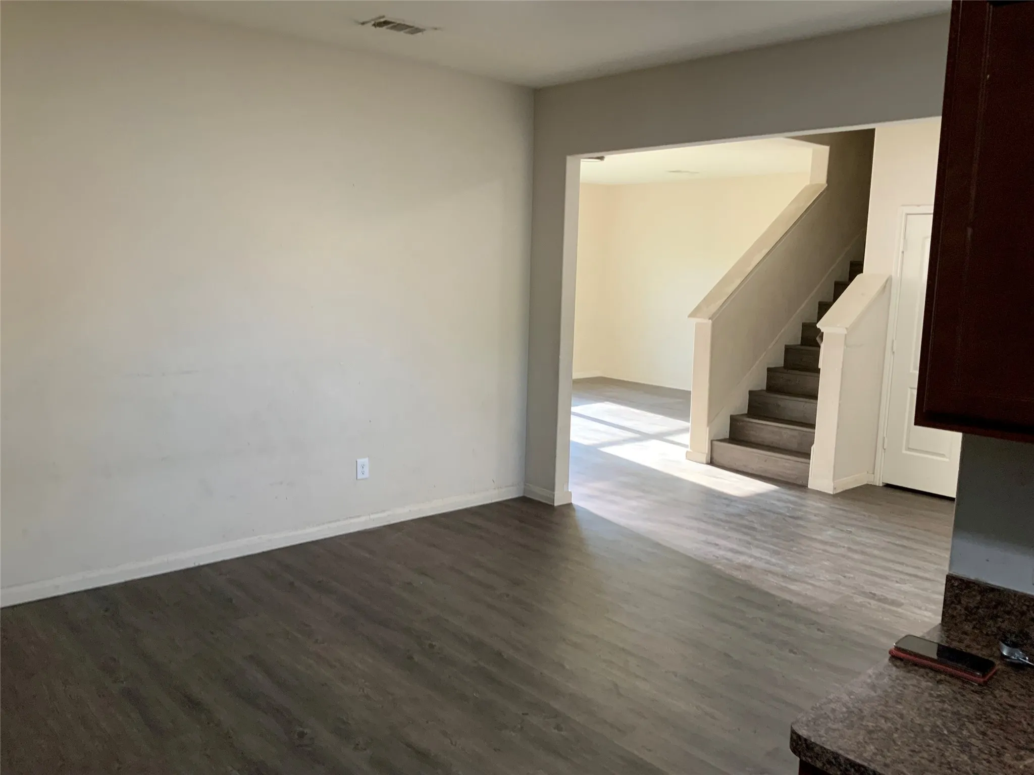 Wood-finish flooring throughout, light-toned wall paint, and a built-in staircase with neutral-toned risers