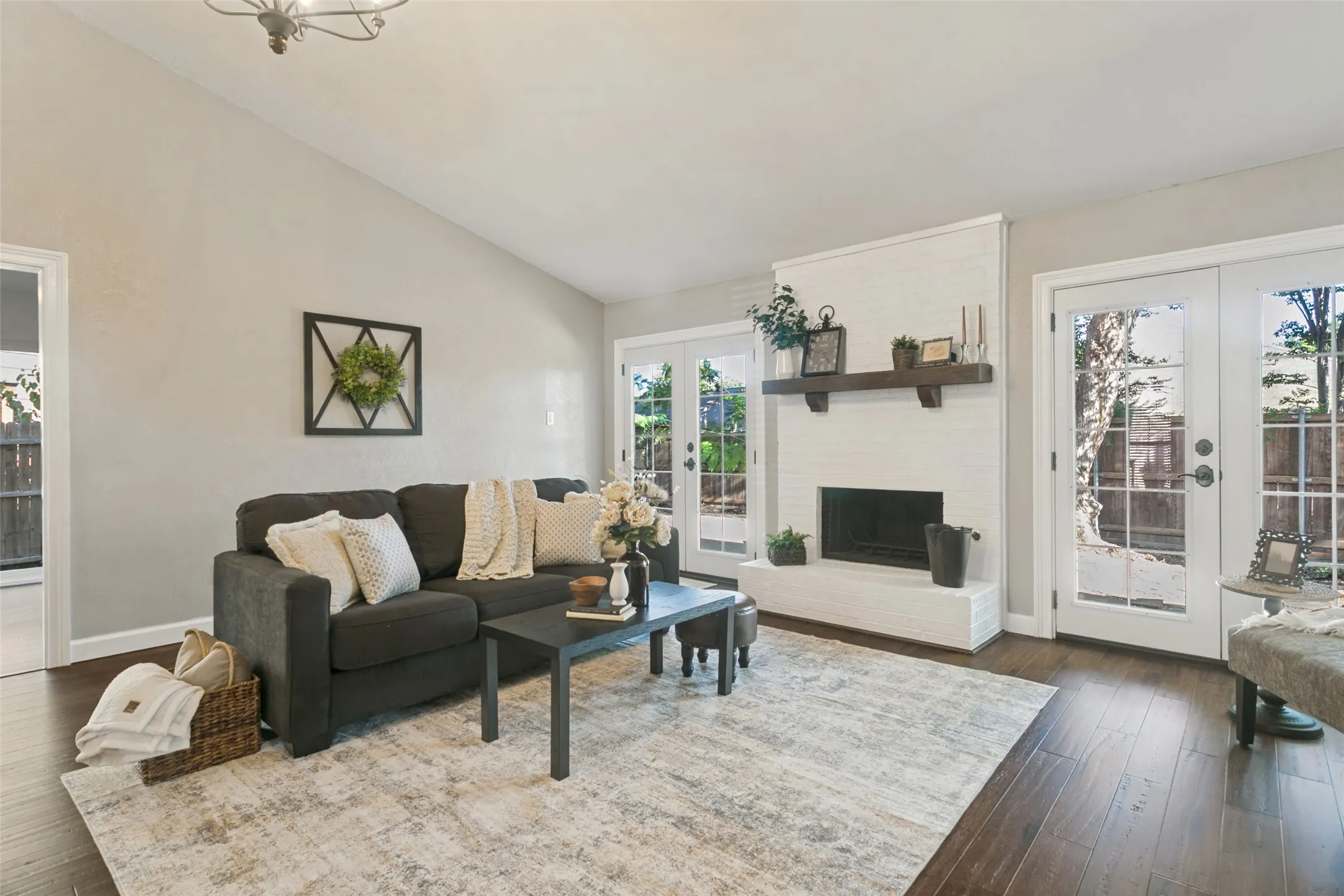 Stunning gas and wood burning fireplace with two sets of double doors leading outside for seamless indoor-outdoor living.