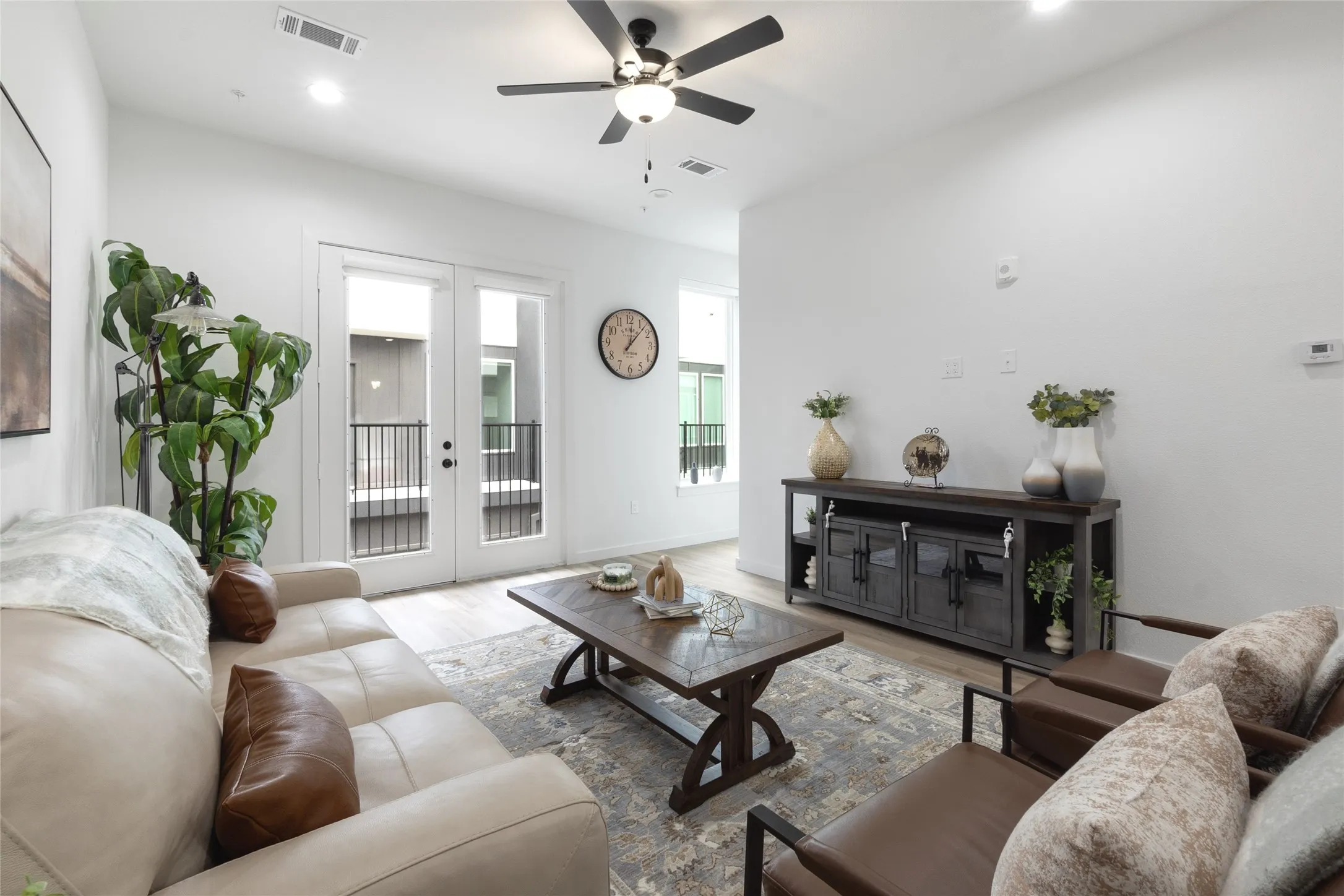 Recessed lighting, wood-finish flooring, white walls, black ceiling fan, and double patio doors with black railings