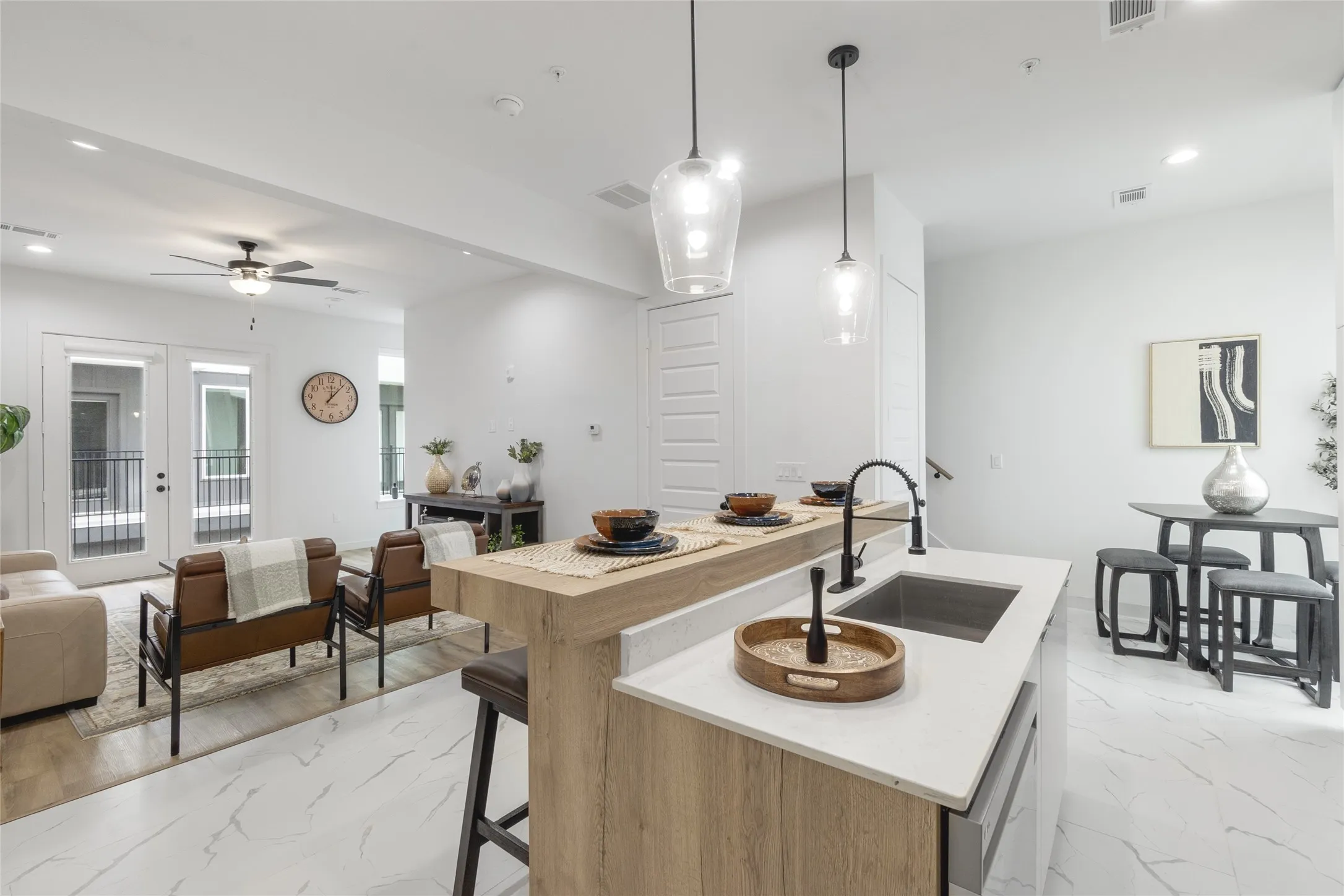 Open-concept living space featuring wood-finish flooring, white walls, recessed lighting, and a modern kitchen island with pendant lighting