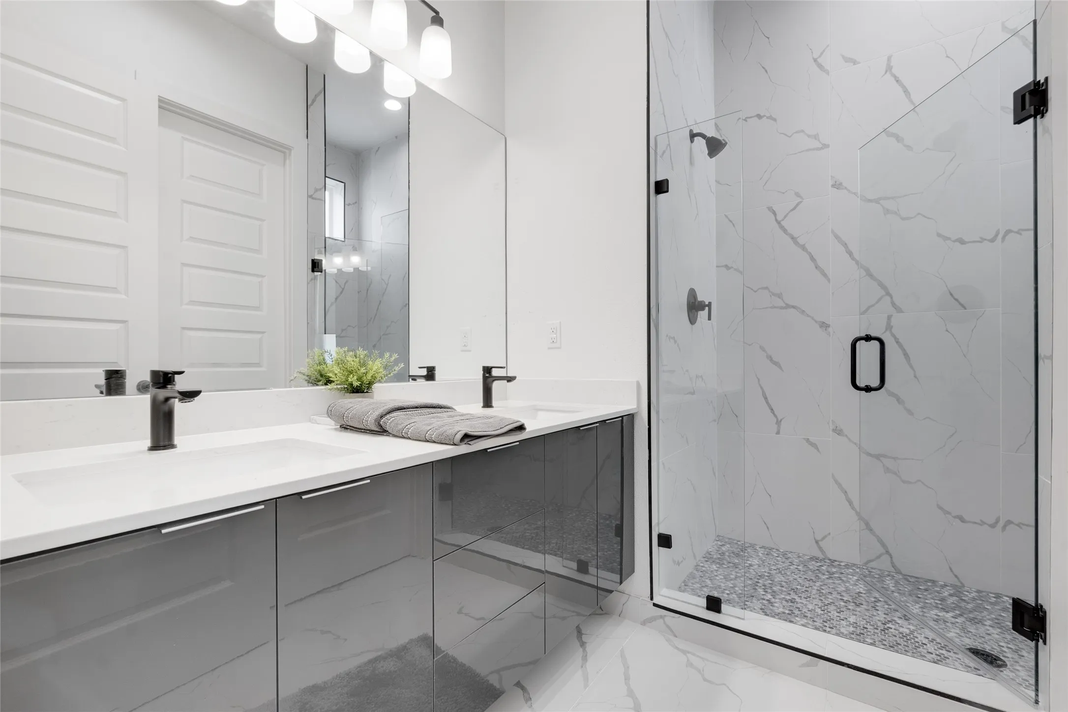 Dual vanity with undermount sinks, gray high-gloss cabinetry, and matte black faucets