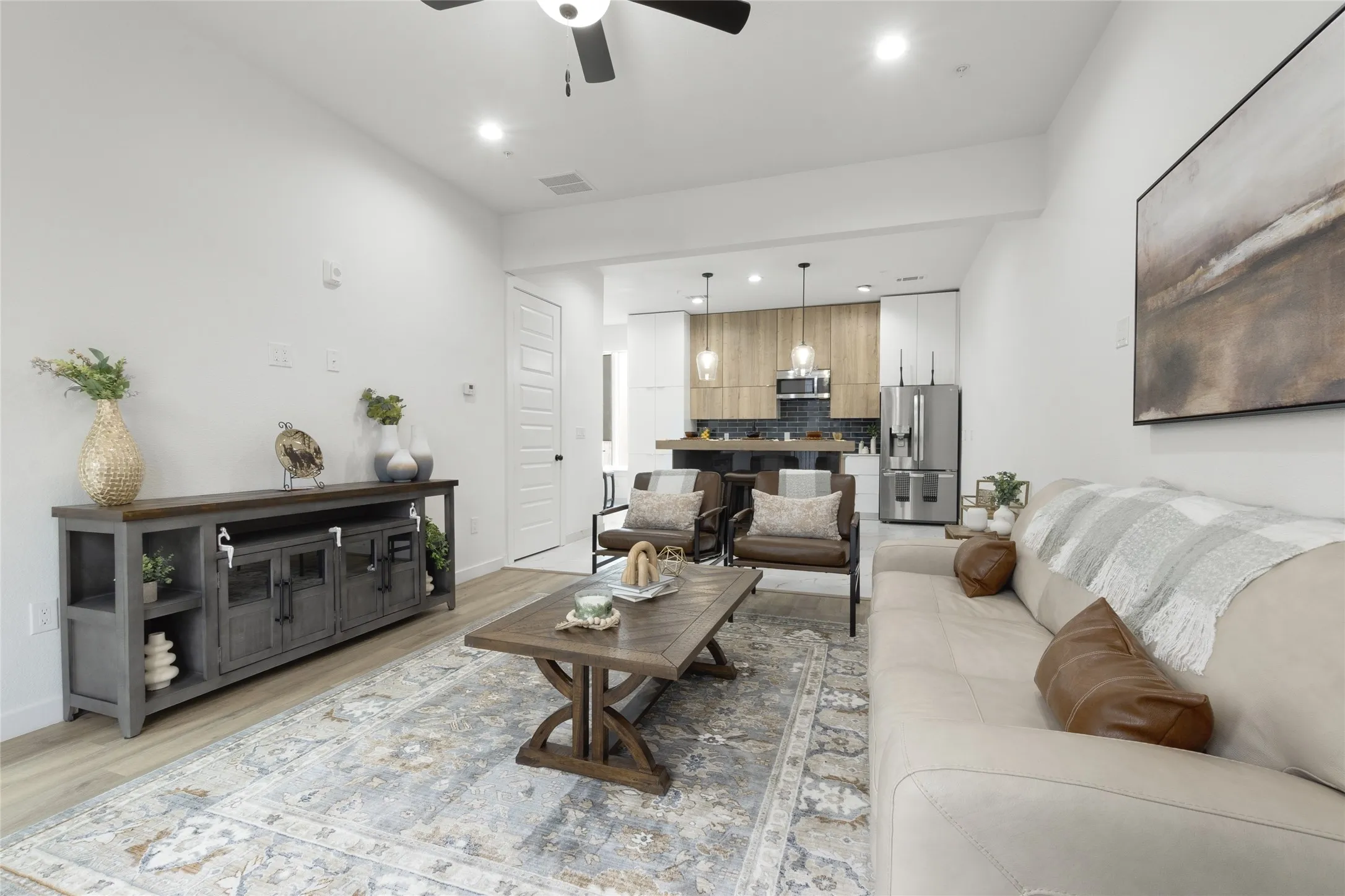Open-concept living space with wood-finish flooring, recessed lighting, and a ceiling fan