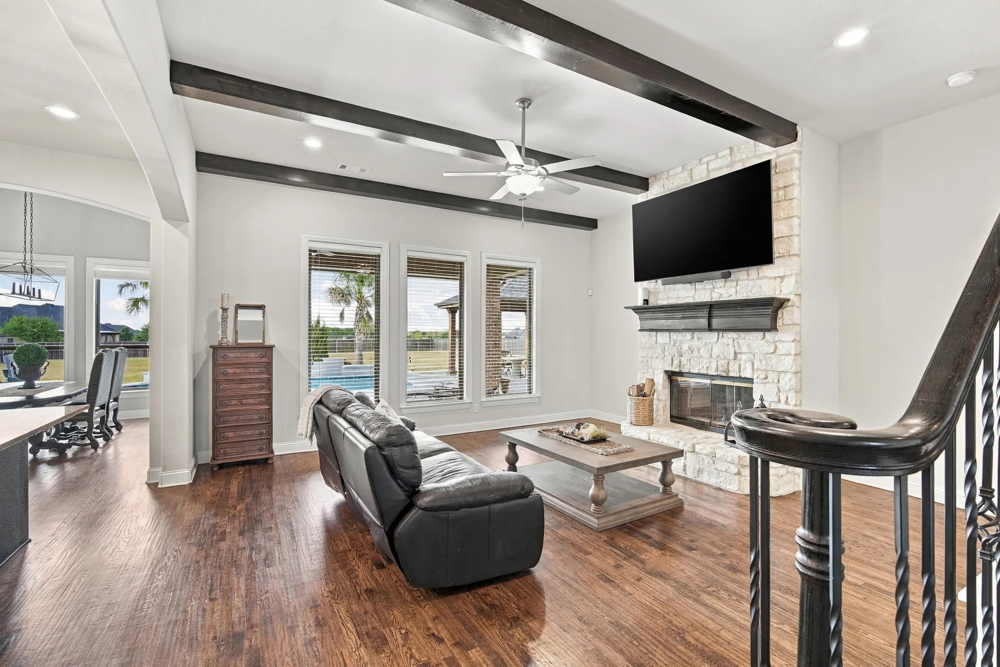 High ceilings with wood beams, a stone fireplace, and a gorgeous view in this sunny living room.