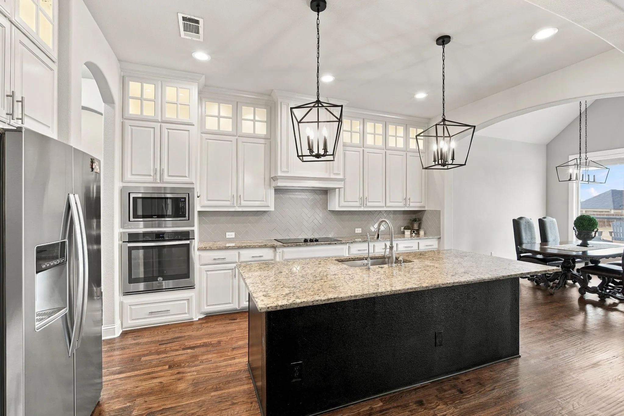 Kitchen is a chef's dream with hardwood floors, upper cabinet lighting, granite countertops, and  beautiful lighting