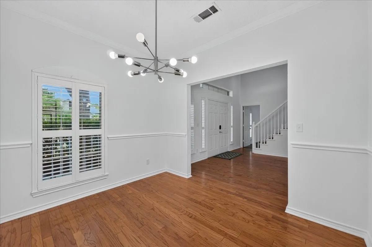 Hardwood-finish flooring, contemporary chandelier, plantation shutters, crown molding, and wainscoting