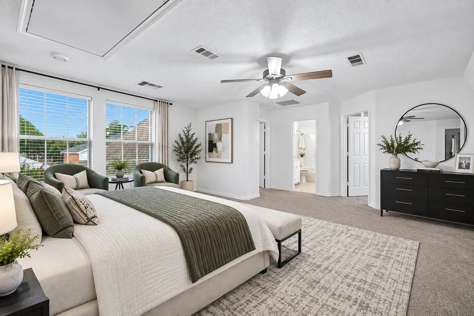 Carpeted bedroom featuring two large windows, a ceiling fan, and access to an en-suite bathroom