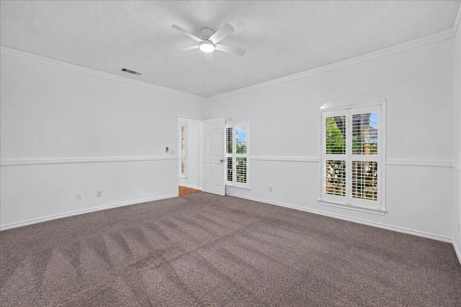 Neutral gray carpet with white walls, crown molding, and wainscoting