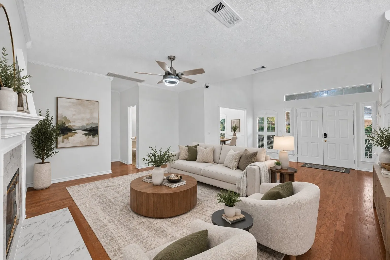 Vaulted ceiling with a ceiling fan, wood-finish flooring, white double entry doors, marble-clad fireplace, and transom windows