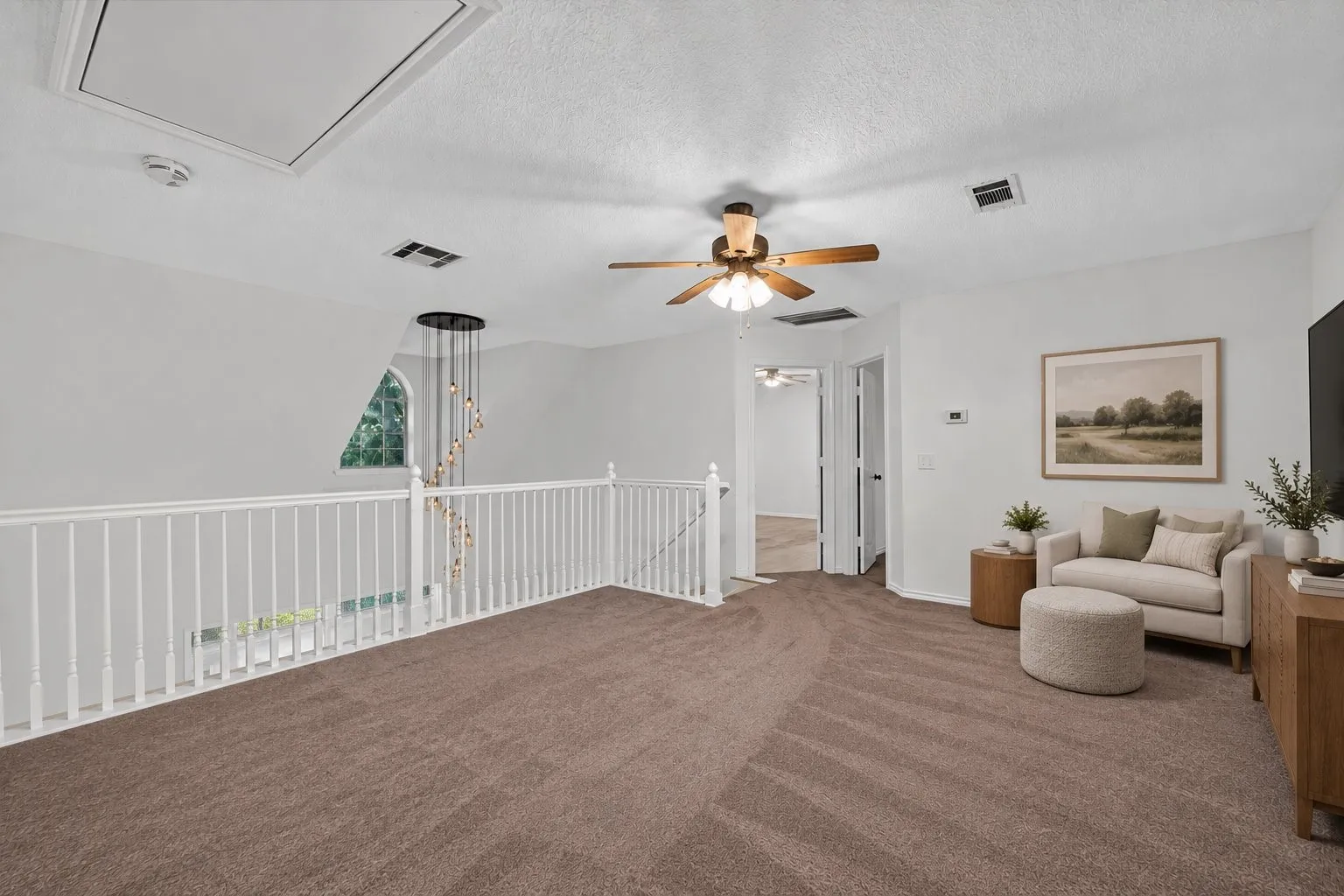 Carpeted upper-level landing with white railing, ceiling fan, and recessed lighting