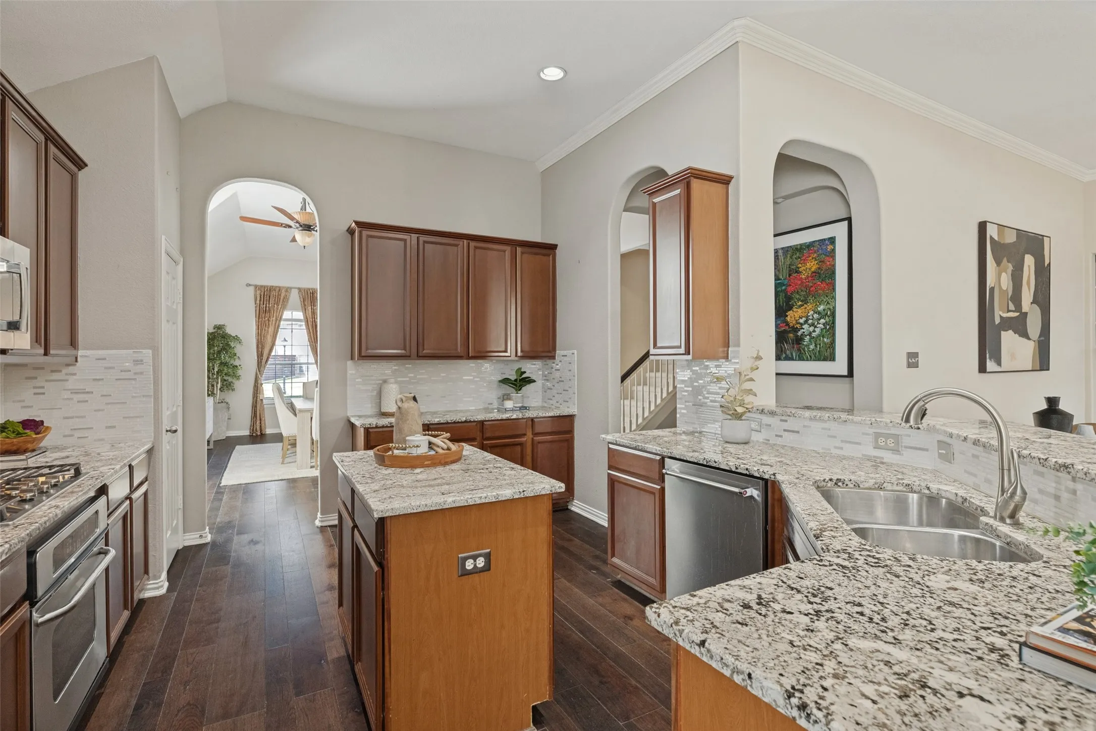 Spacious kitchen featuring granite countertops, abundant cabinetry, stainless steel appliances, a center island, and an open design that keeps the kitchen connected to the surrounding living and dining spaces.