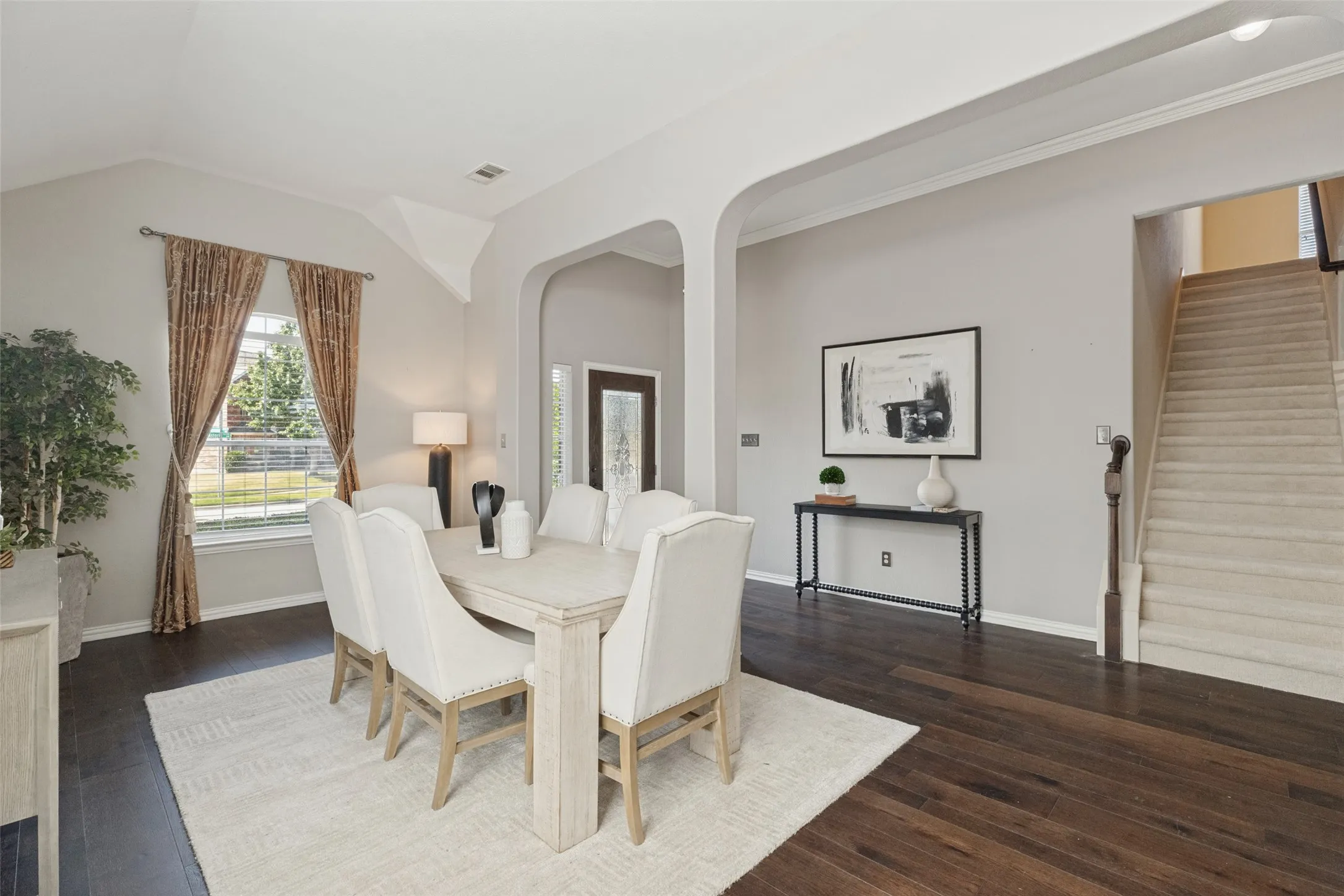 Spacious formal dining area featuring rich hardwood floors, soaring ceilings, graceful architectural arches, and abundant natural light—perfect for entertaining family and friends.