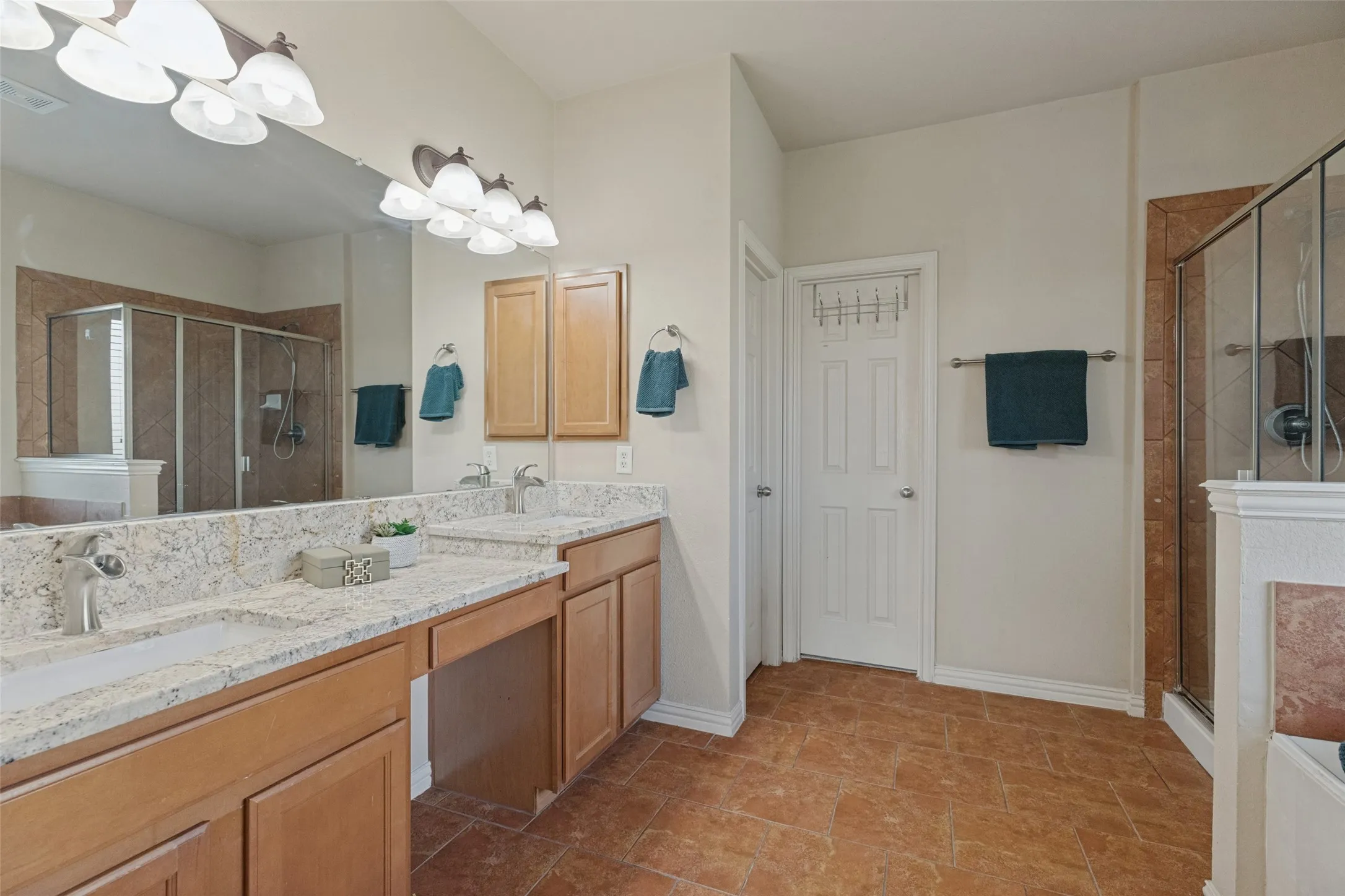 Spacious primary bath features dual vanities with granite countertops, abundant storage, and a large mirror, offering plenty of space for everyday routines.