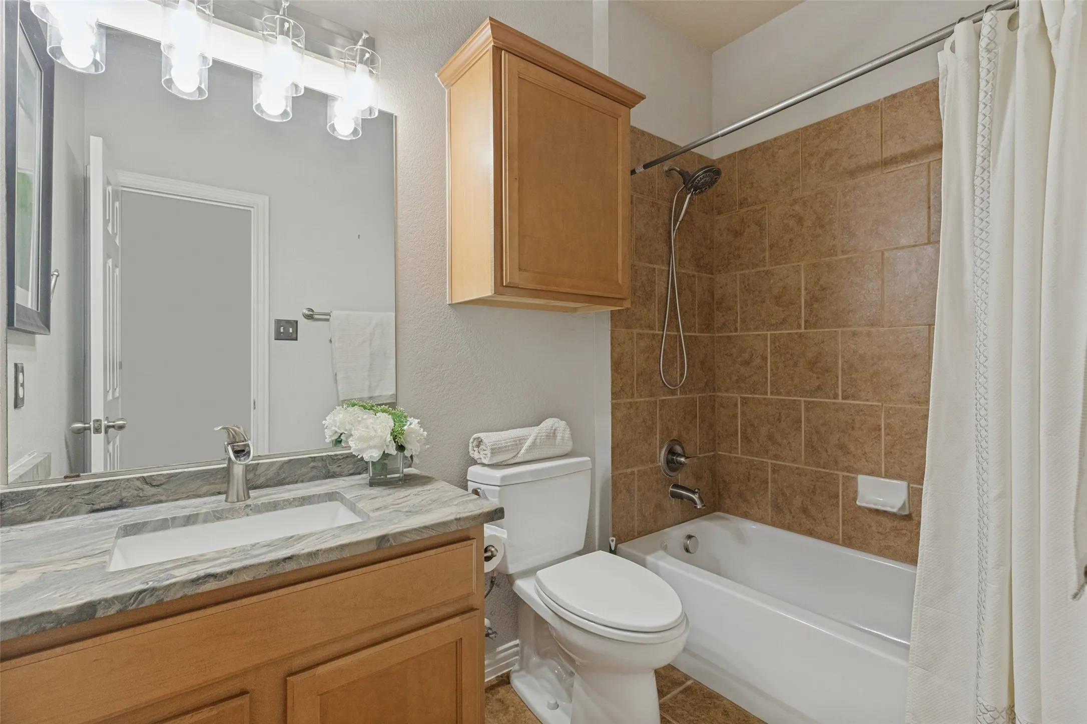 Secondary full bath features a granite countertop, generous vanity storage, and a tub-shower combination with tile surround.