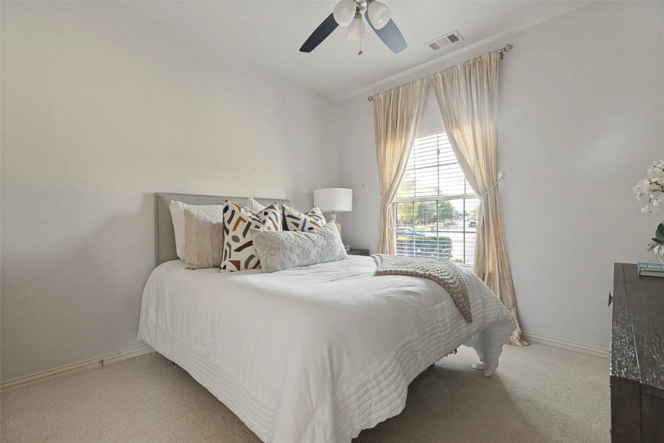 Secondary bedroom offers brand-new carpet, a ceiling fan, and a large window providing plenty of natural light.