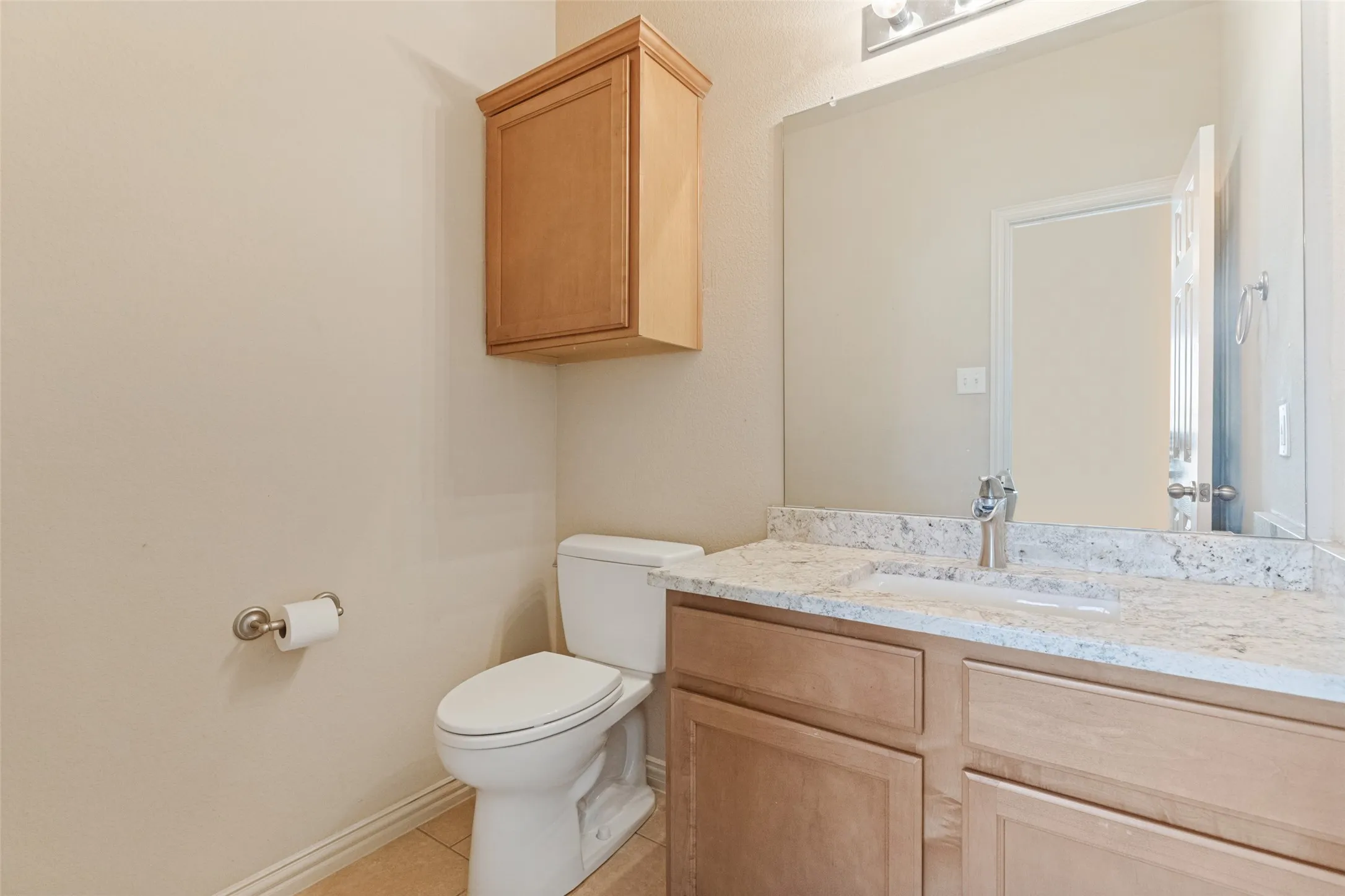 Convenient upstairs half bath featuring a granite countertop, ample vanity storage, and a clean, neutral design