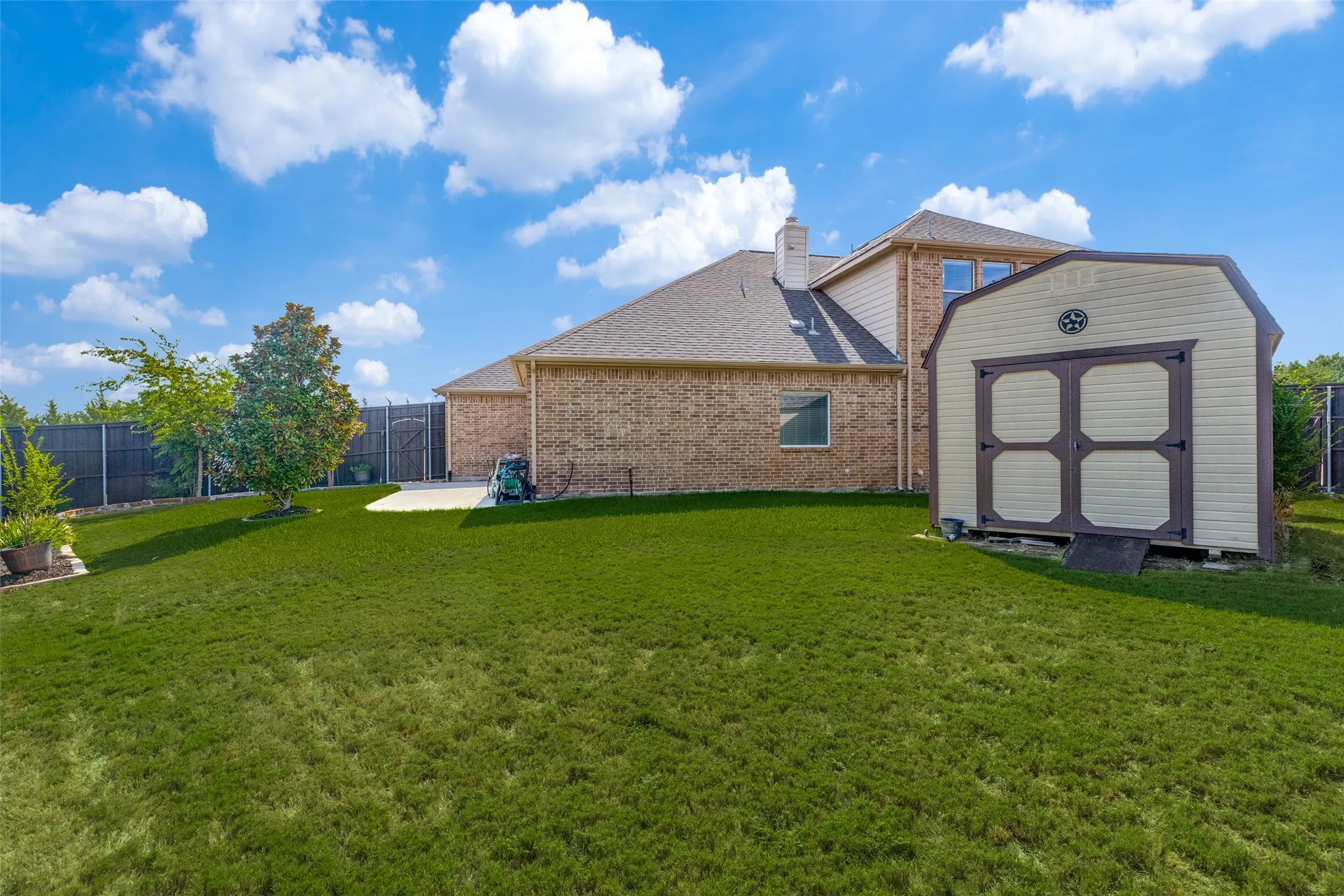 Expansive fenced backyard offers plenty of green space for outdoor activities, pets, or entertaining, plus a convenient storage shed for lawn and gardening equipment.