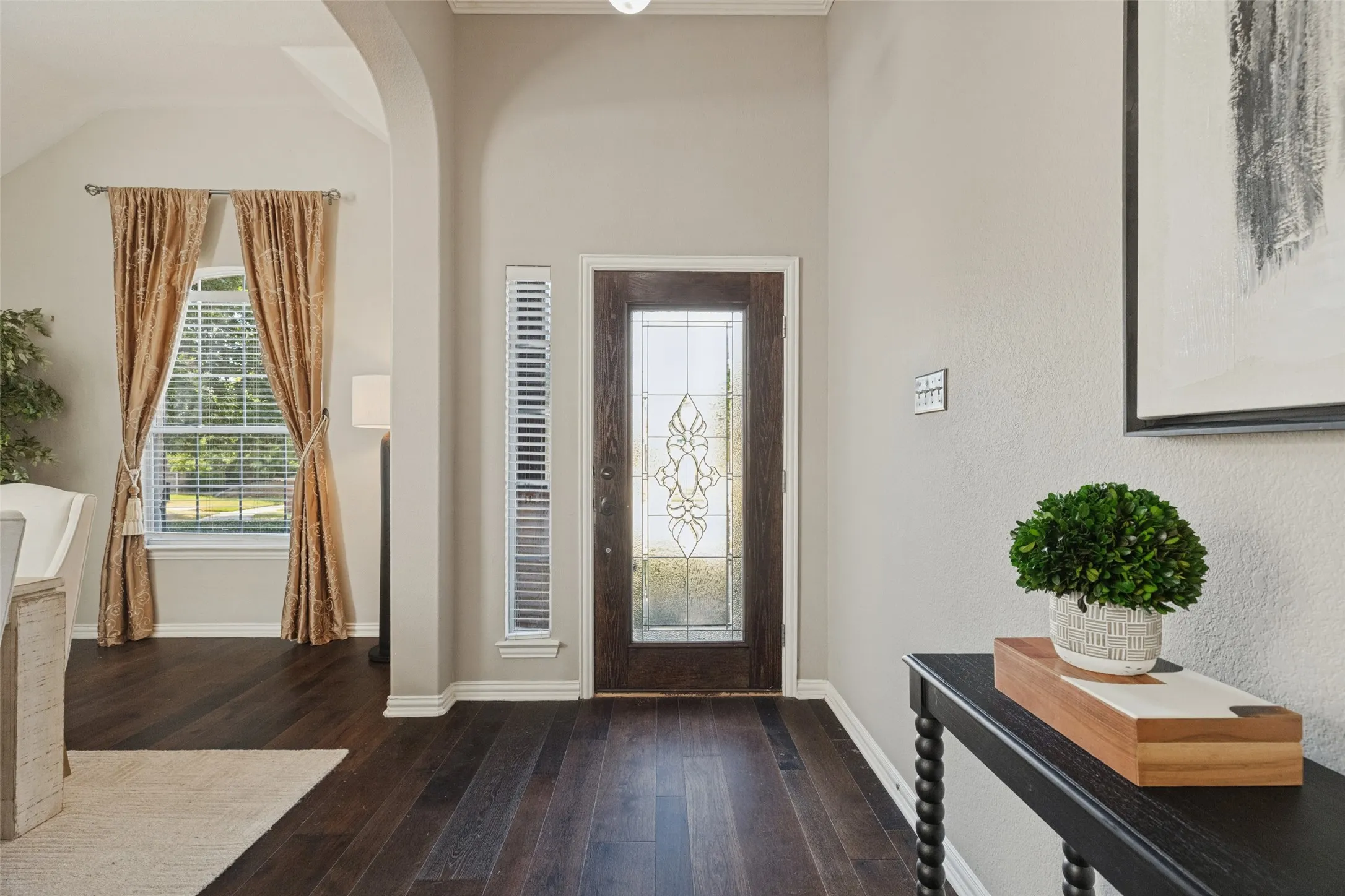 A warm and welcoming entry featuring rich hardwood floors, soaring ceilings, and a beautiful decorative glass front door that fills the space with natural light..