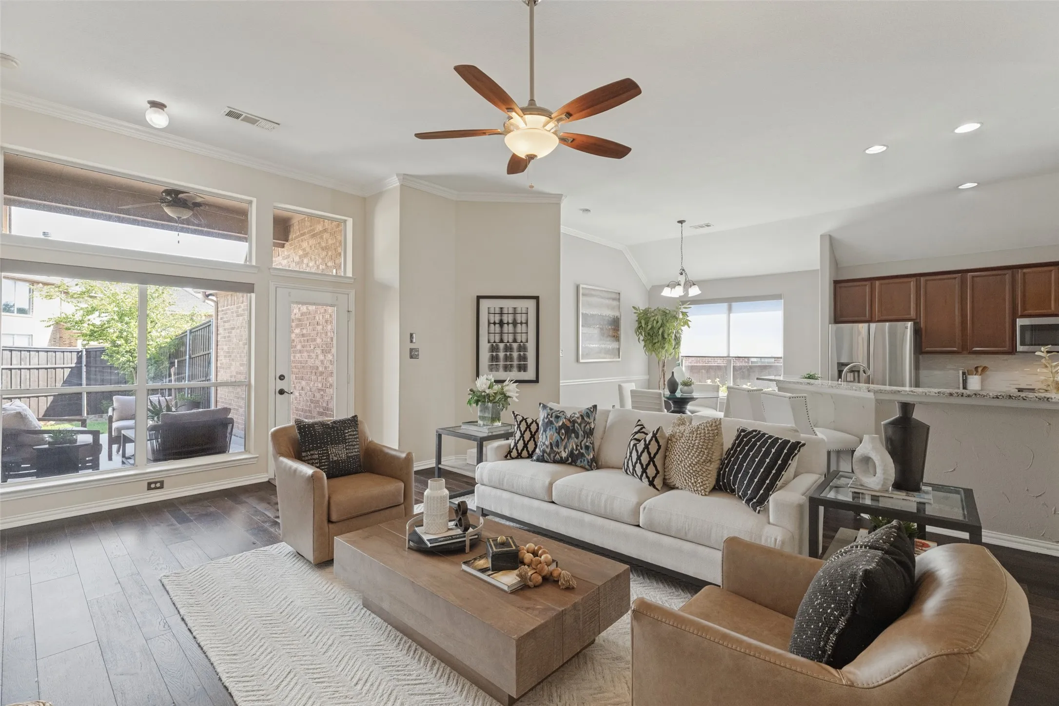 Spacious living area with soaring ceilings and rich hardwood floors flows seamlessly into the kitchen and breakfast nook, while oversized windows fill the room with natural light and overlook the covered patio.
