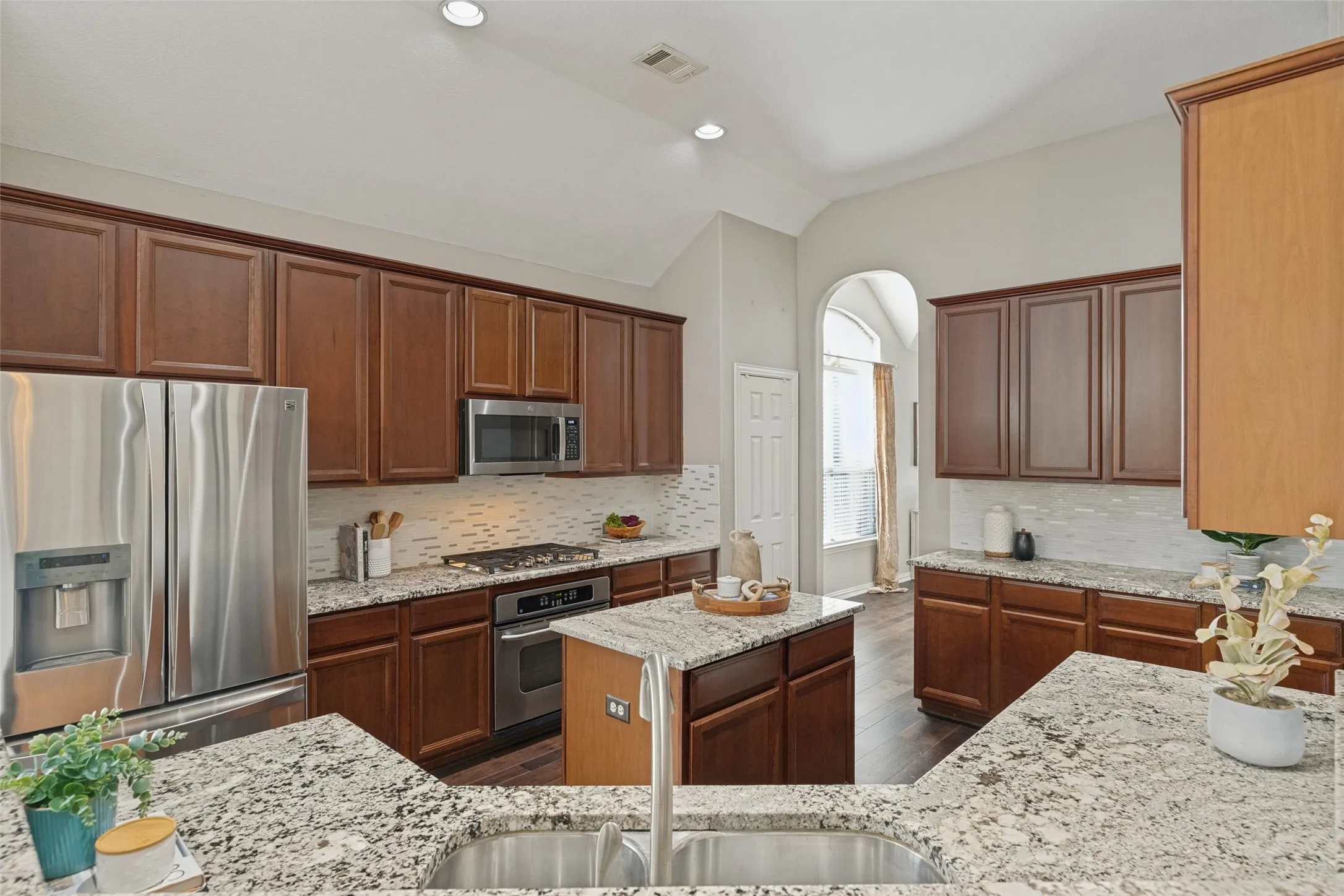 Spacious kitchen showcasing extensive cabinetry, granite countertops, stainless steel appliances, a center island, gas cooktop, and generous counter space for meal prep and entertaining.