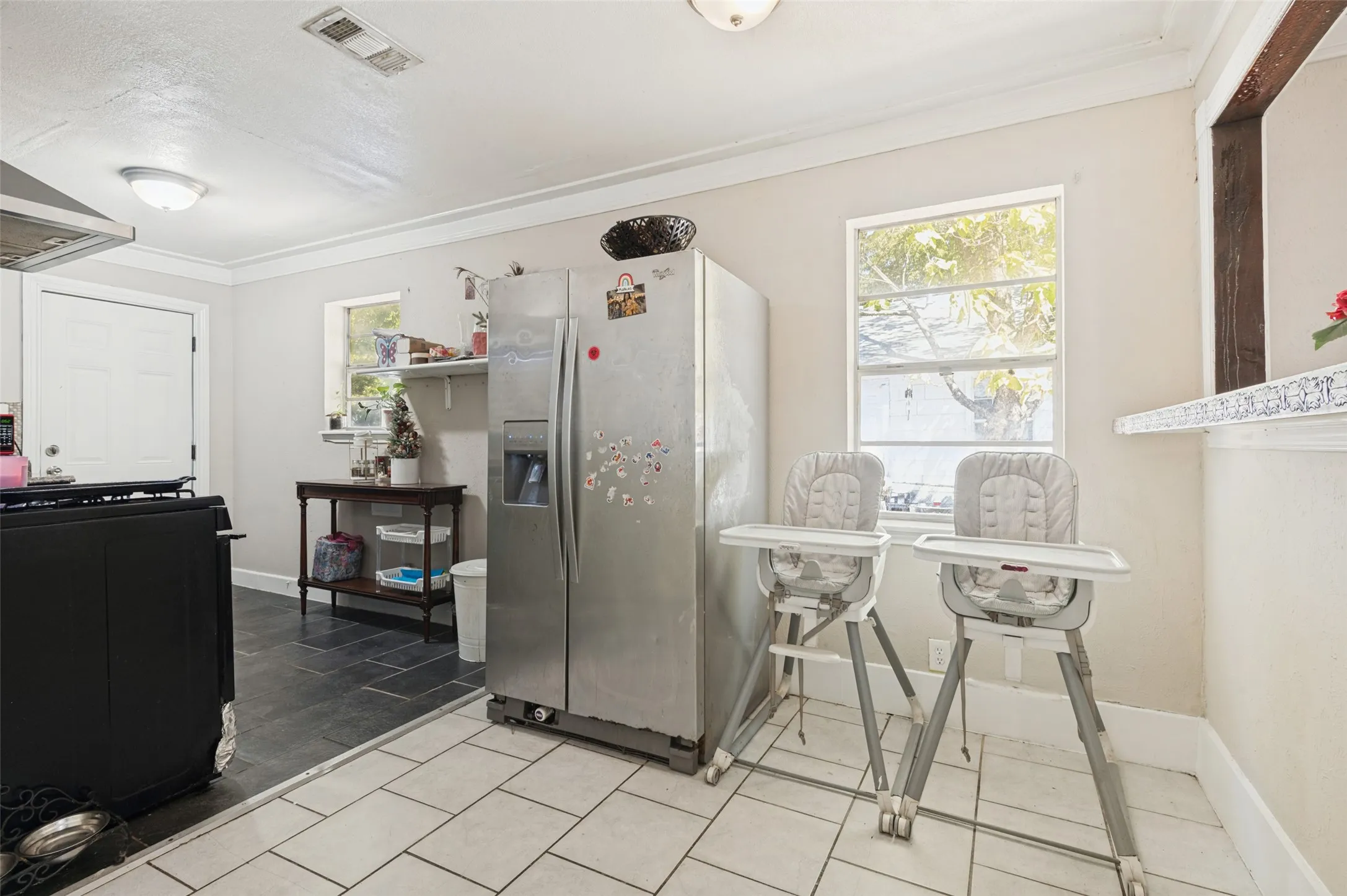 Recessed lighting, crown molding, white tile flooring, stainless steel refrigerator, and dual windows