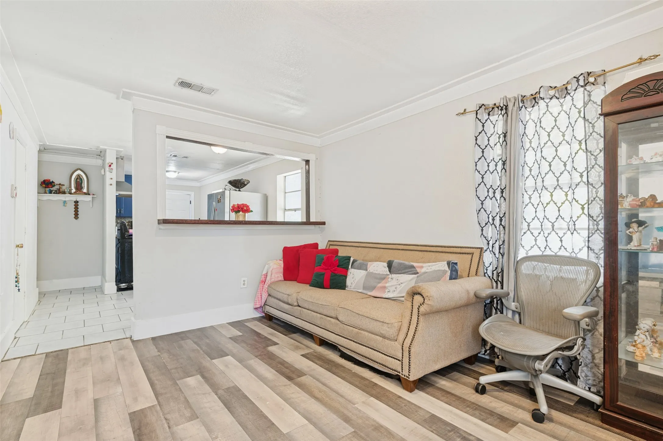 Wood-finish flooring, white walls, crown molding, and a pass-through window with wood trim