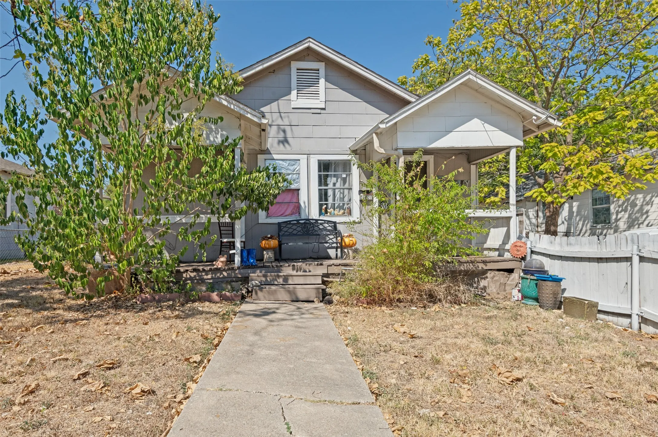 Gable roofline, covered front porch, front yard tree, and a concrete walkway