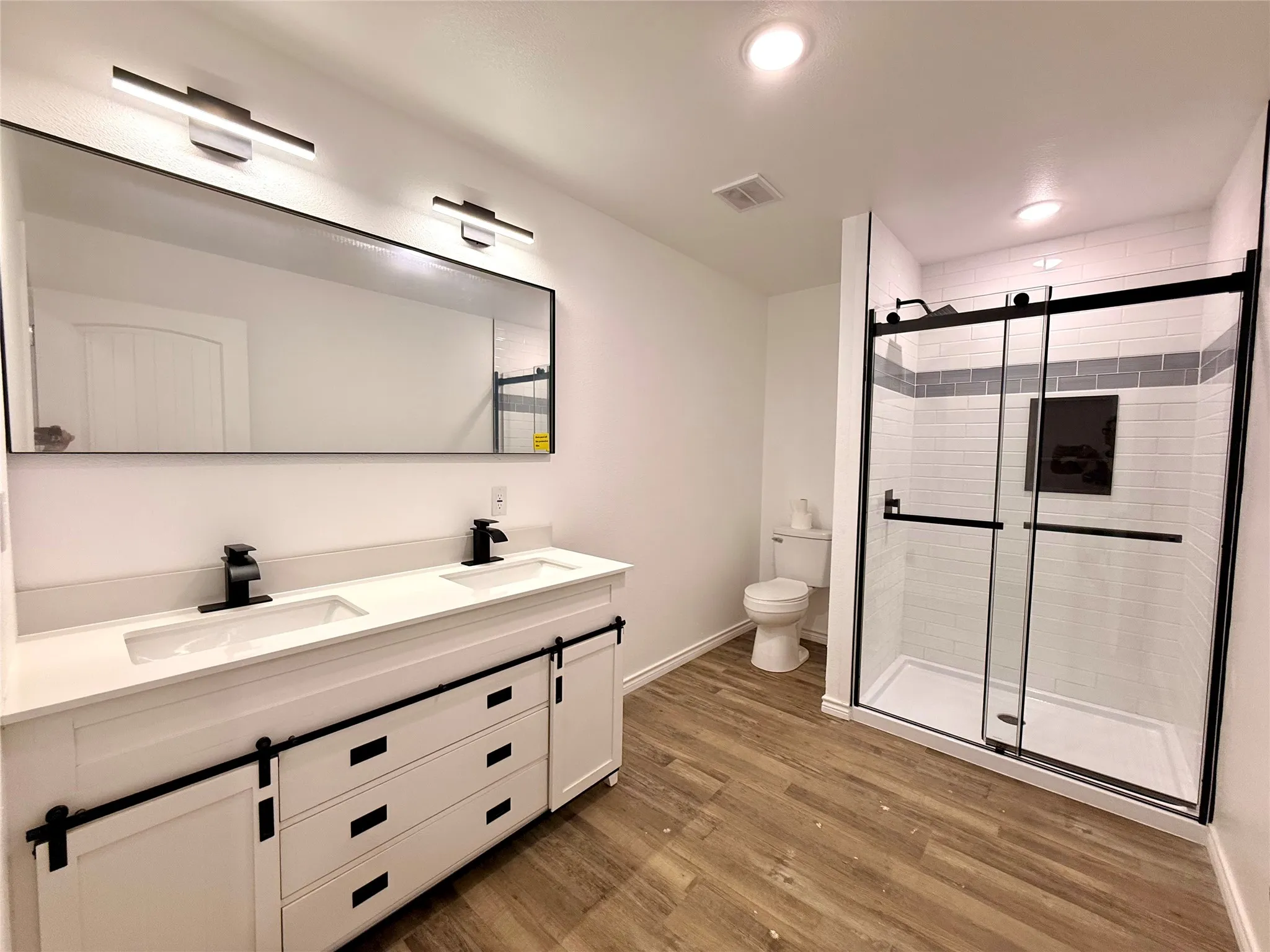 Dual vanity with barn door style cabinetry, quartz countertop, and matte black fixtures