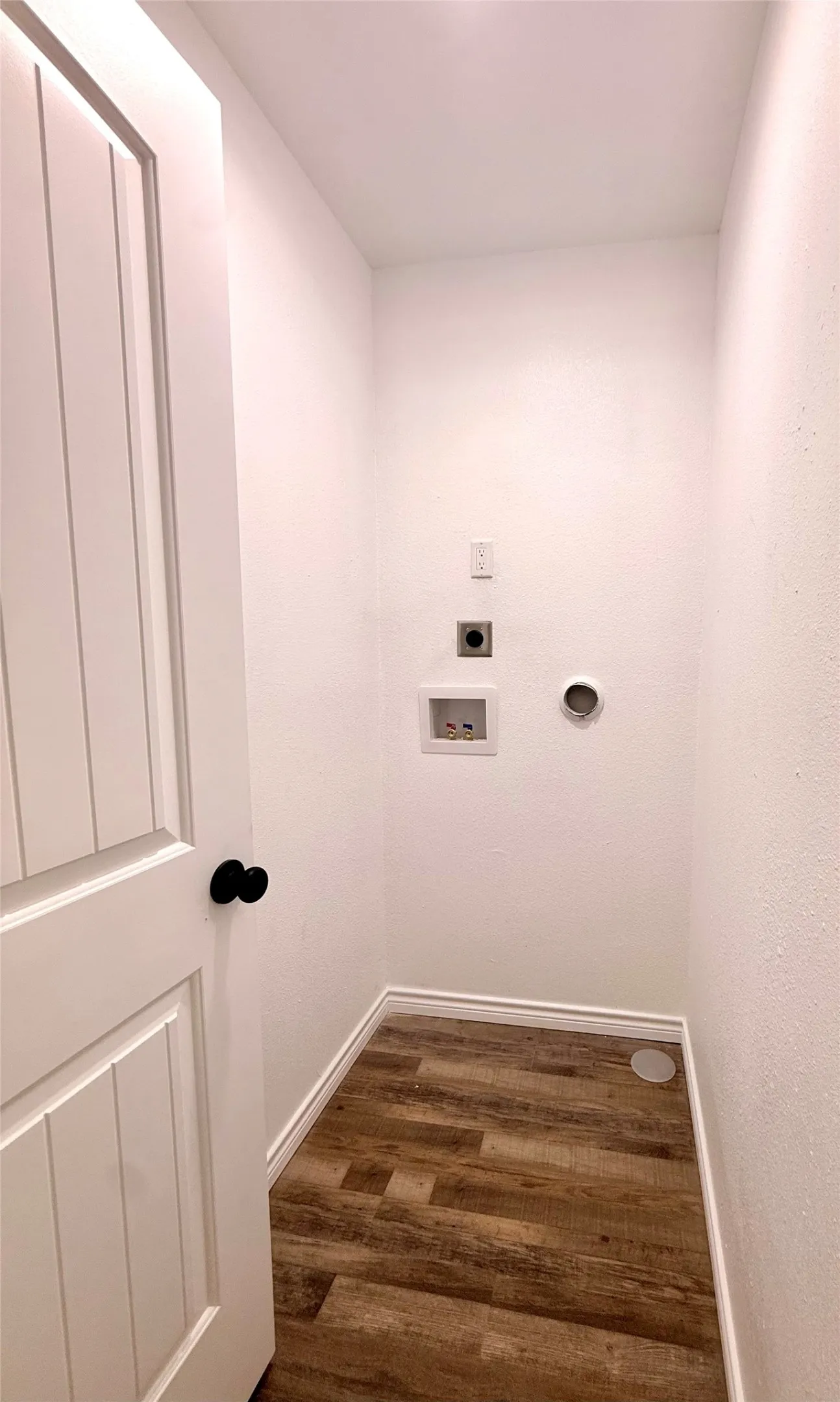 Laundry area with wood-finish flooring and white walls