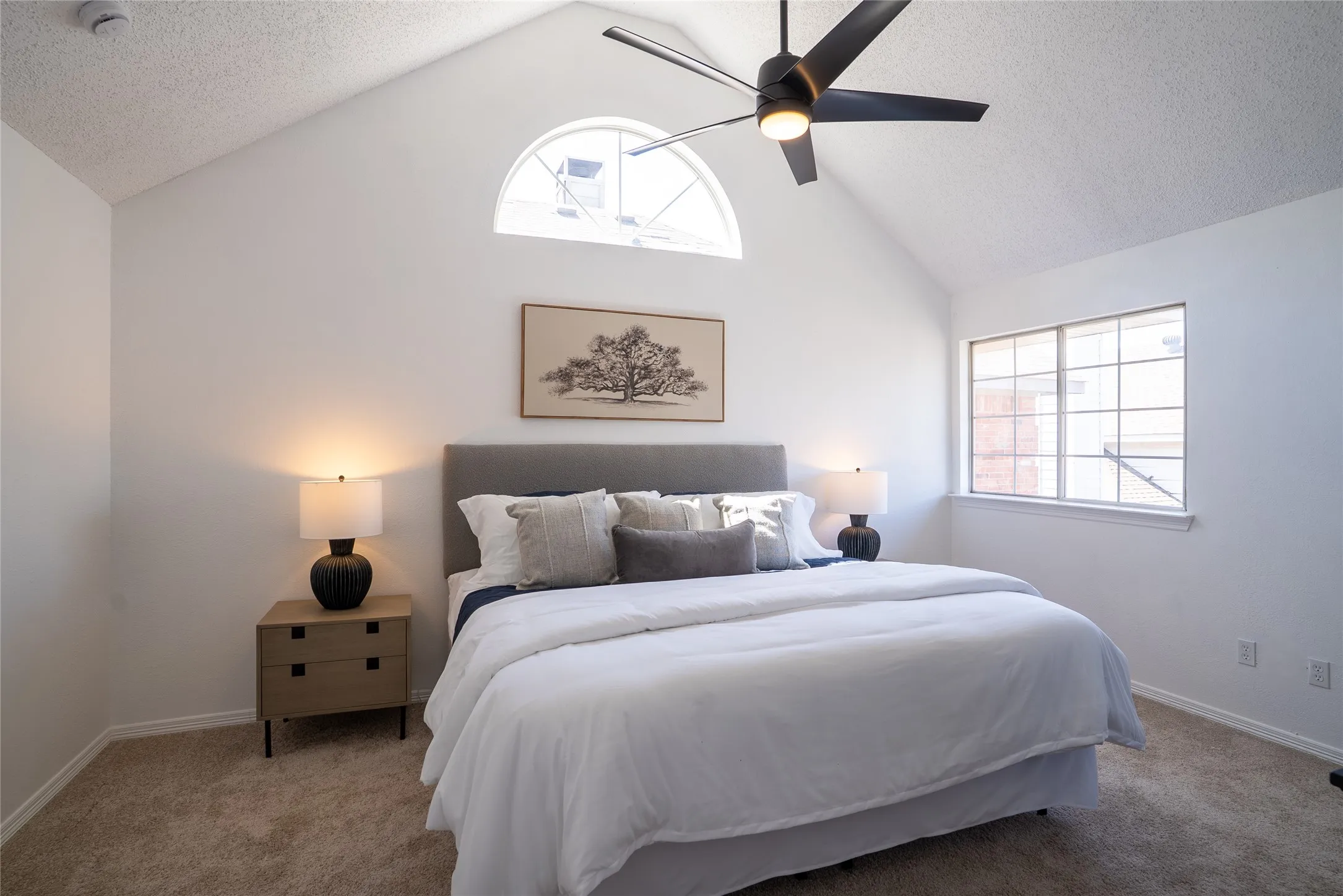 Vaulted ceiling with an arched window and a ceiling fan